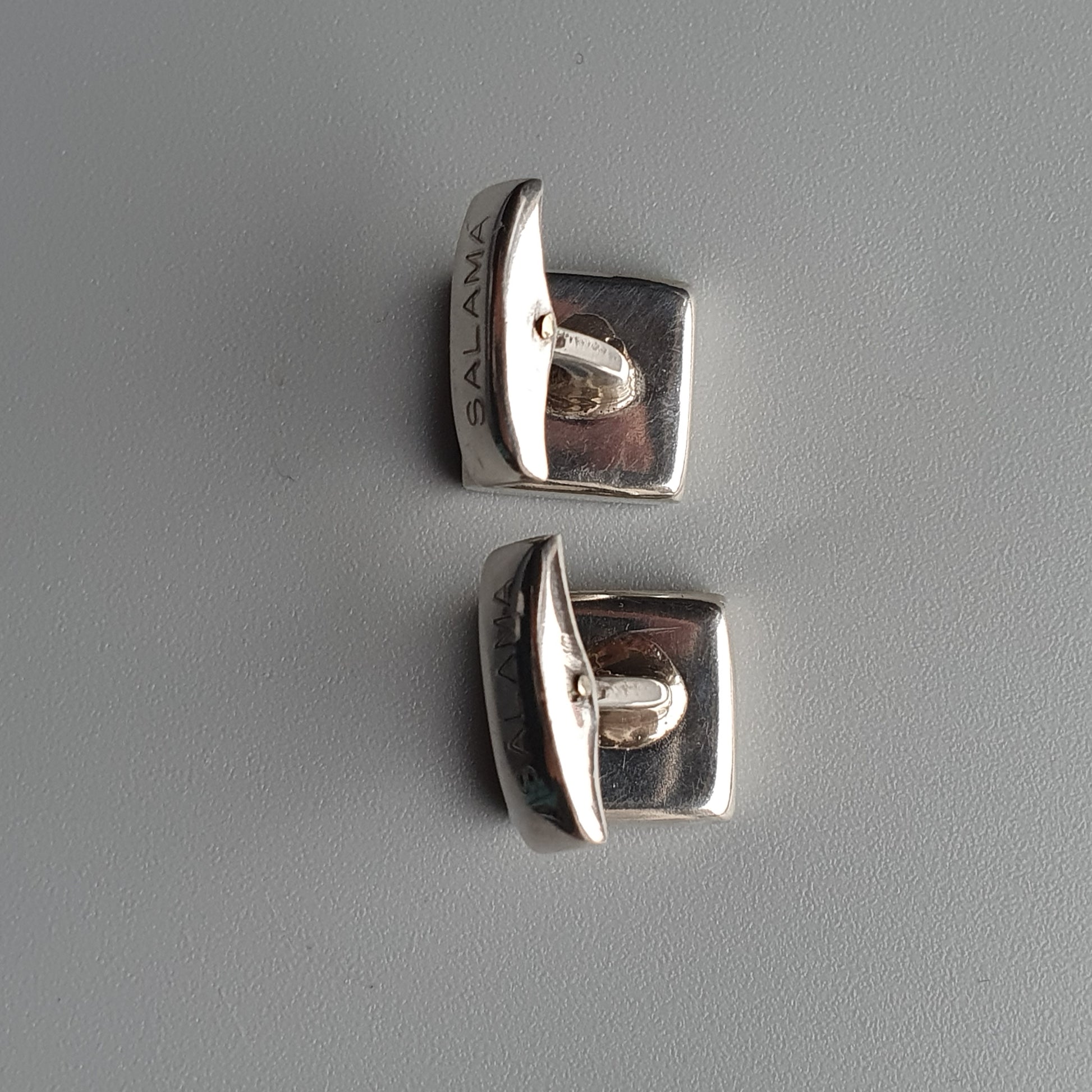 Two square silver cufflinks with curved top edges.