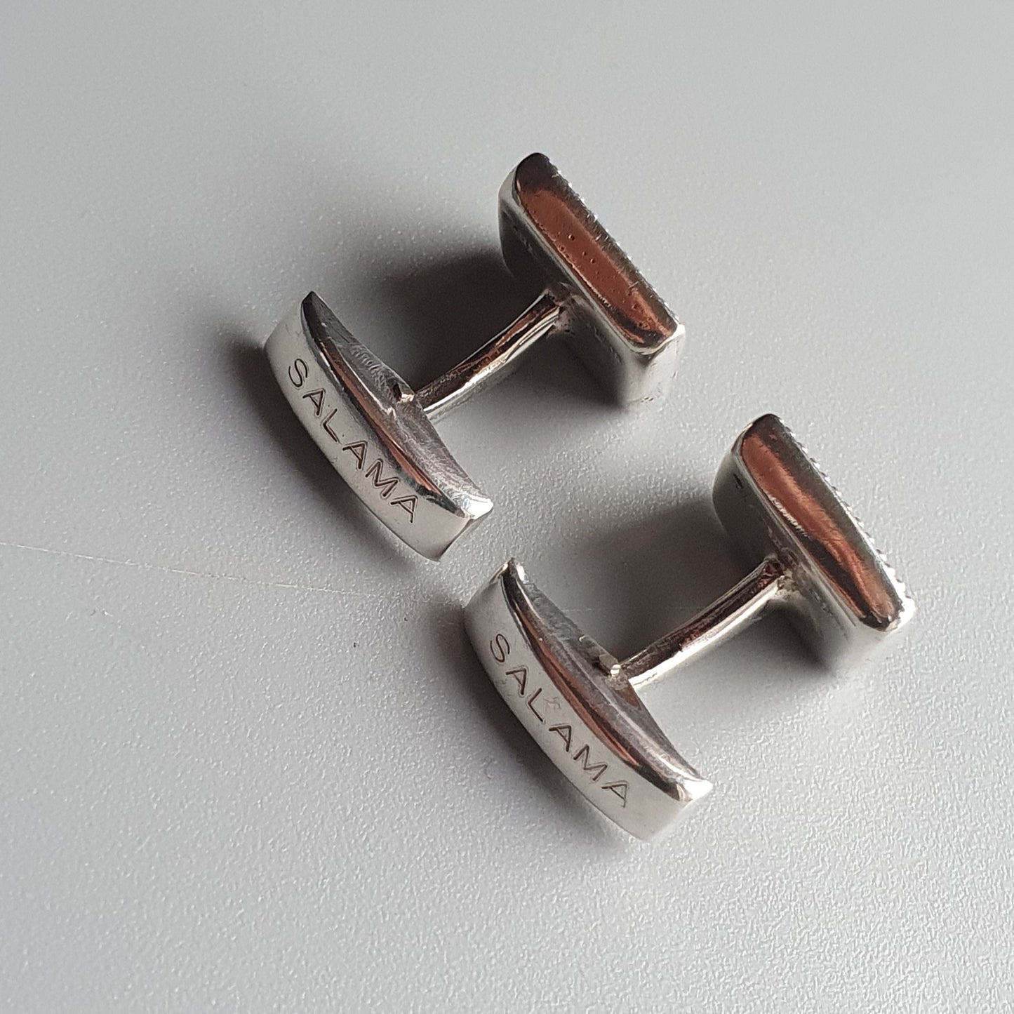 Pair of silver cufflinks with ’SILANA’ engraved on them.