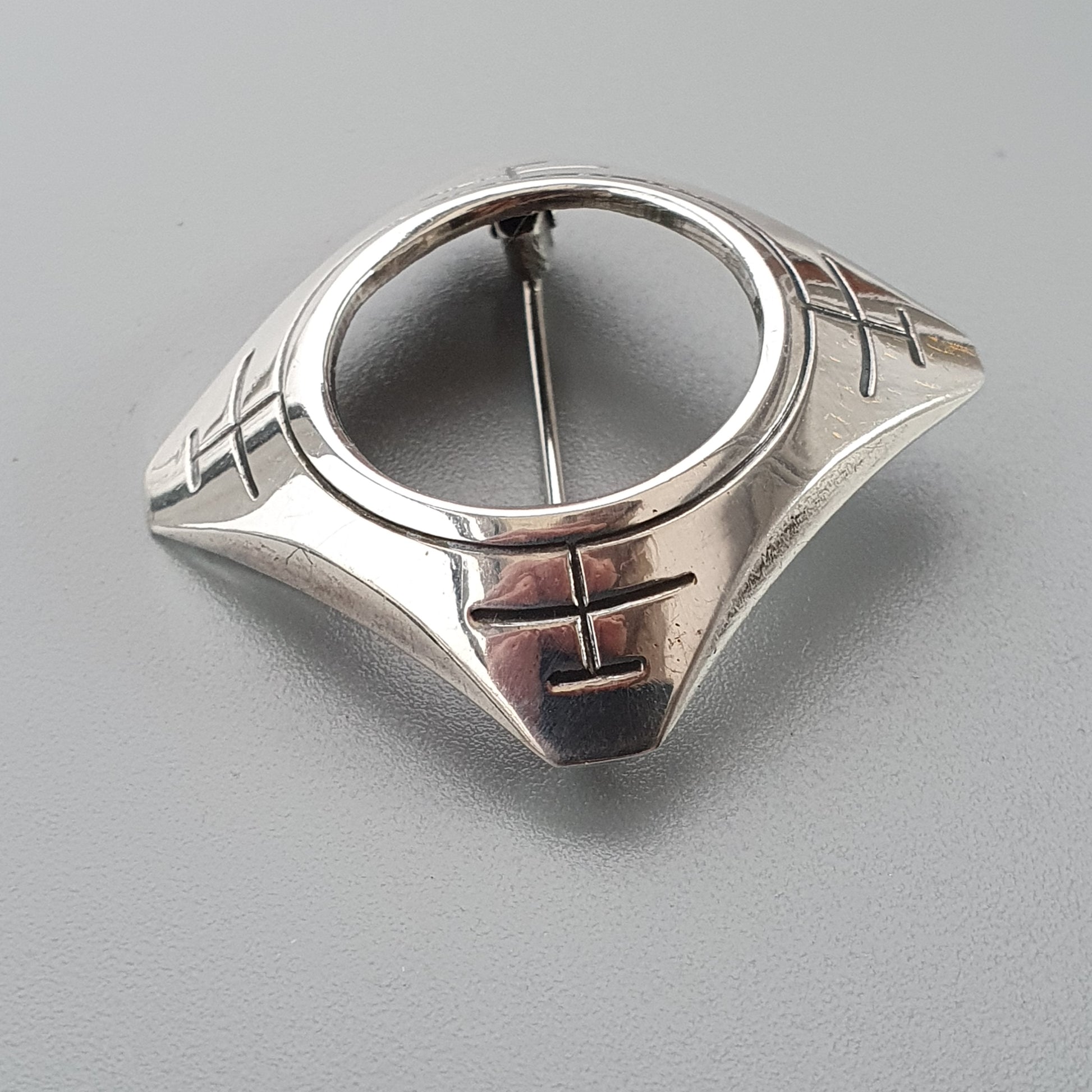 Silver modernist brooch with a circular opening and geometric design elements.