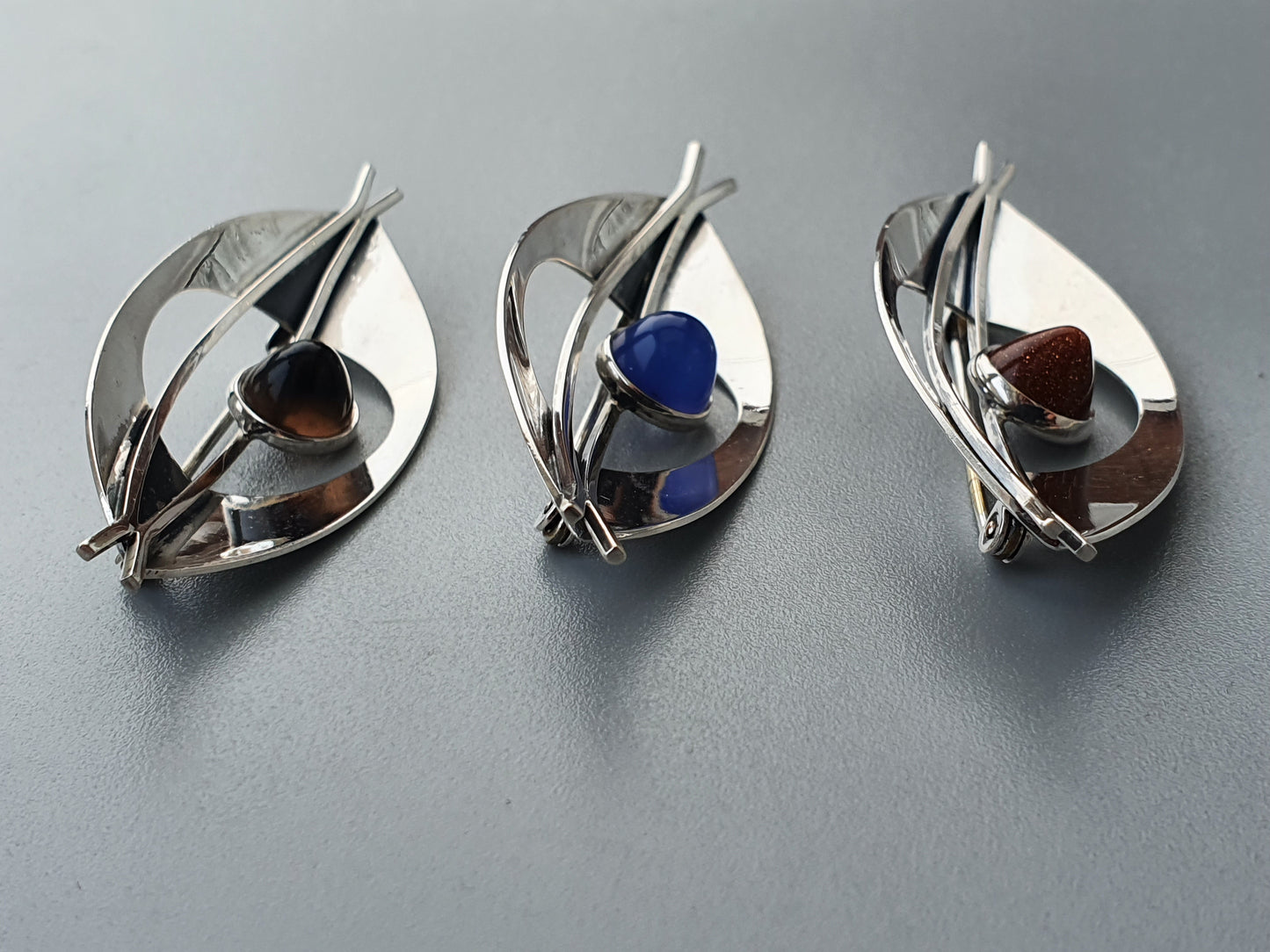 Leaf-shaped silver spoons with colored spheres nestled inside.