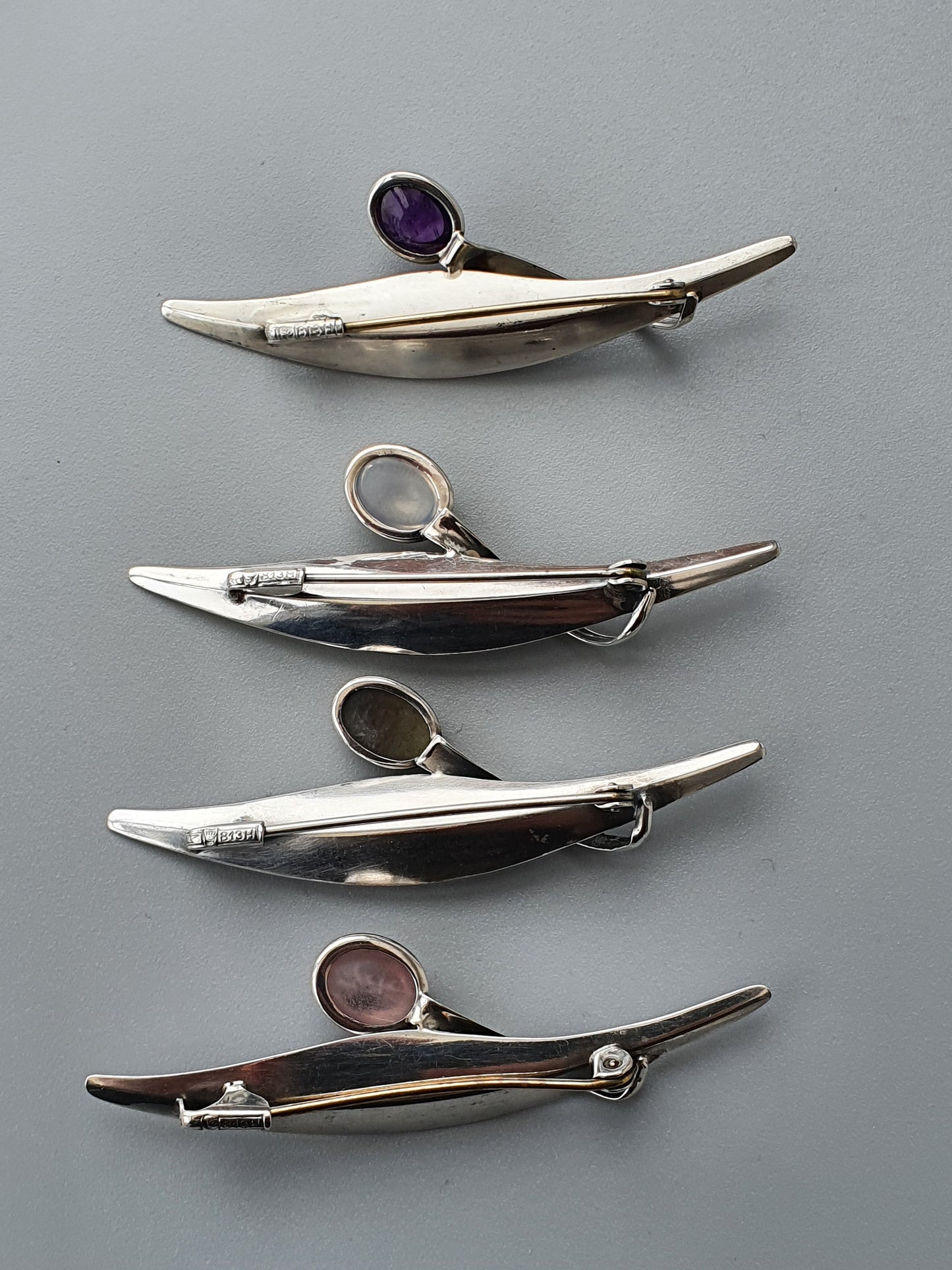 Collection of sleek, modernist silver brooches with gemstone accents.