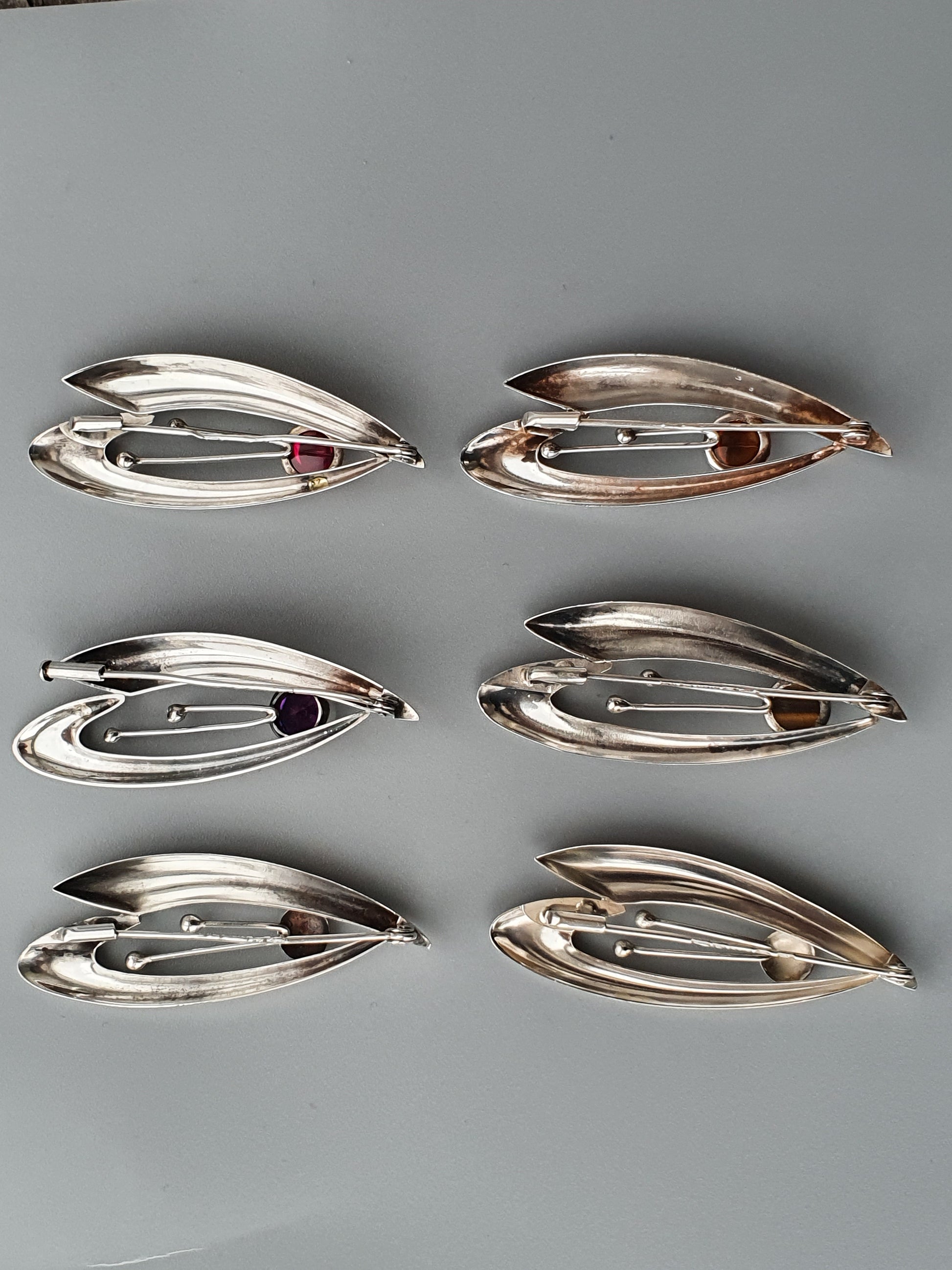 Silver-toned leaf-shaped brooches or pins with small gemstones.