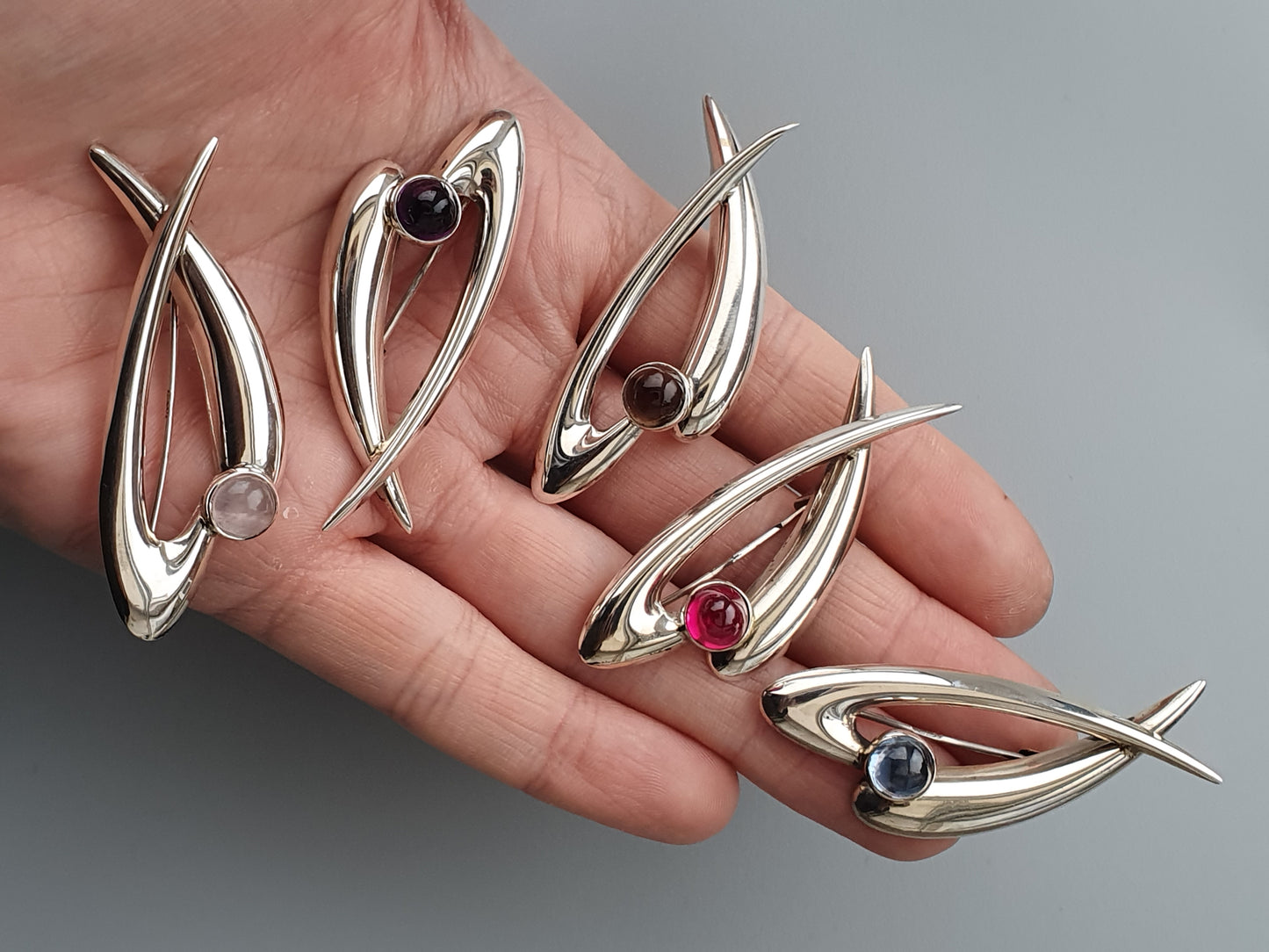 Silver fish-shaped brooches or pins with gemstone eyes.