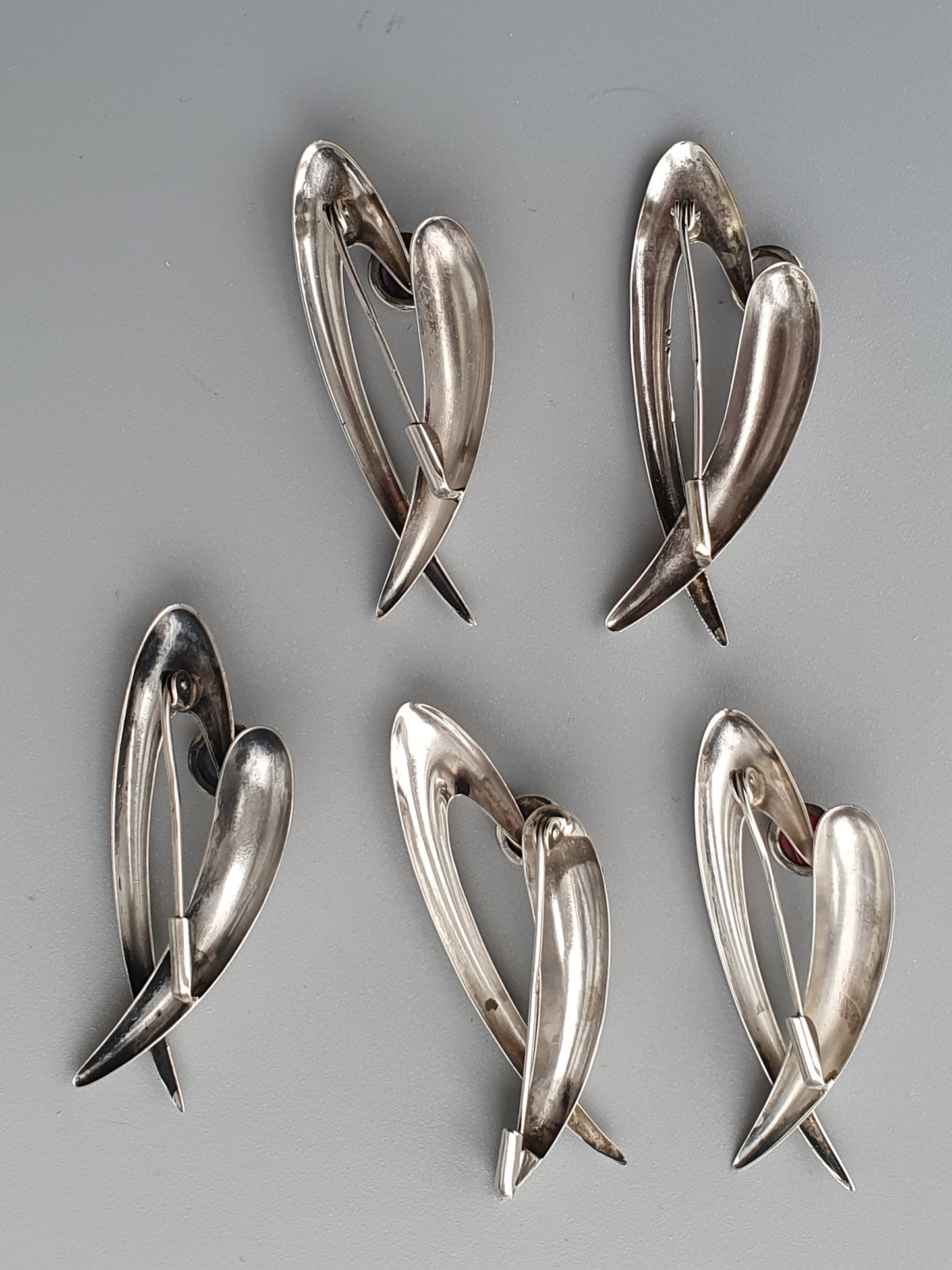 Silver heart-shaped brooches or pins with sleek, modern designs.