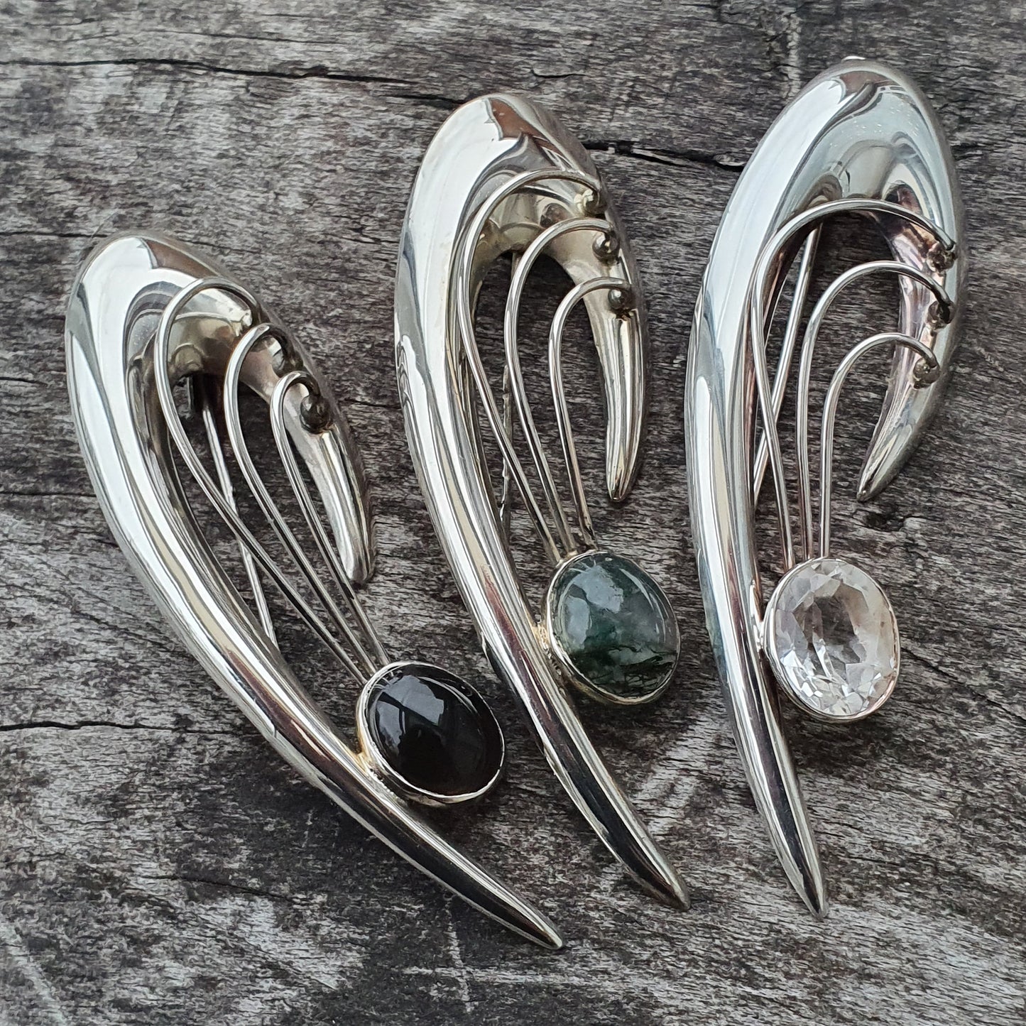 Curved silver brooches or pins with gemstone accents.