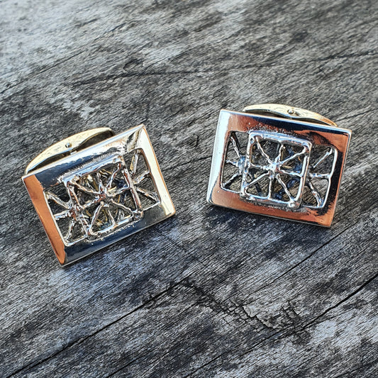 Pair of silver cufflinks with intricate geometric designs.