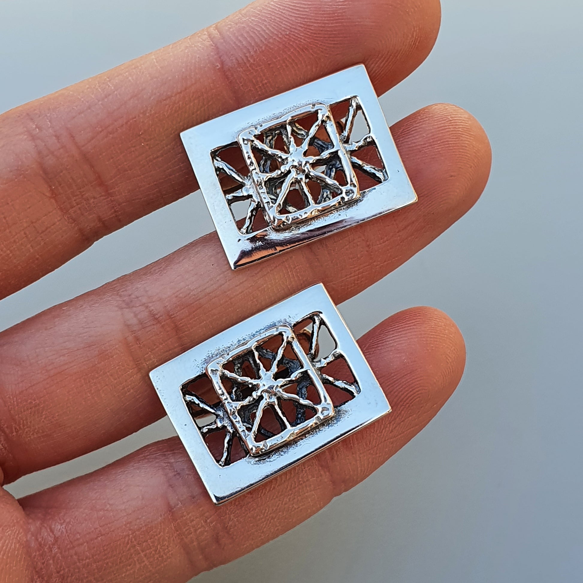 Pair of rectangular silver earrings with intricate geometric cutout designs.