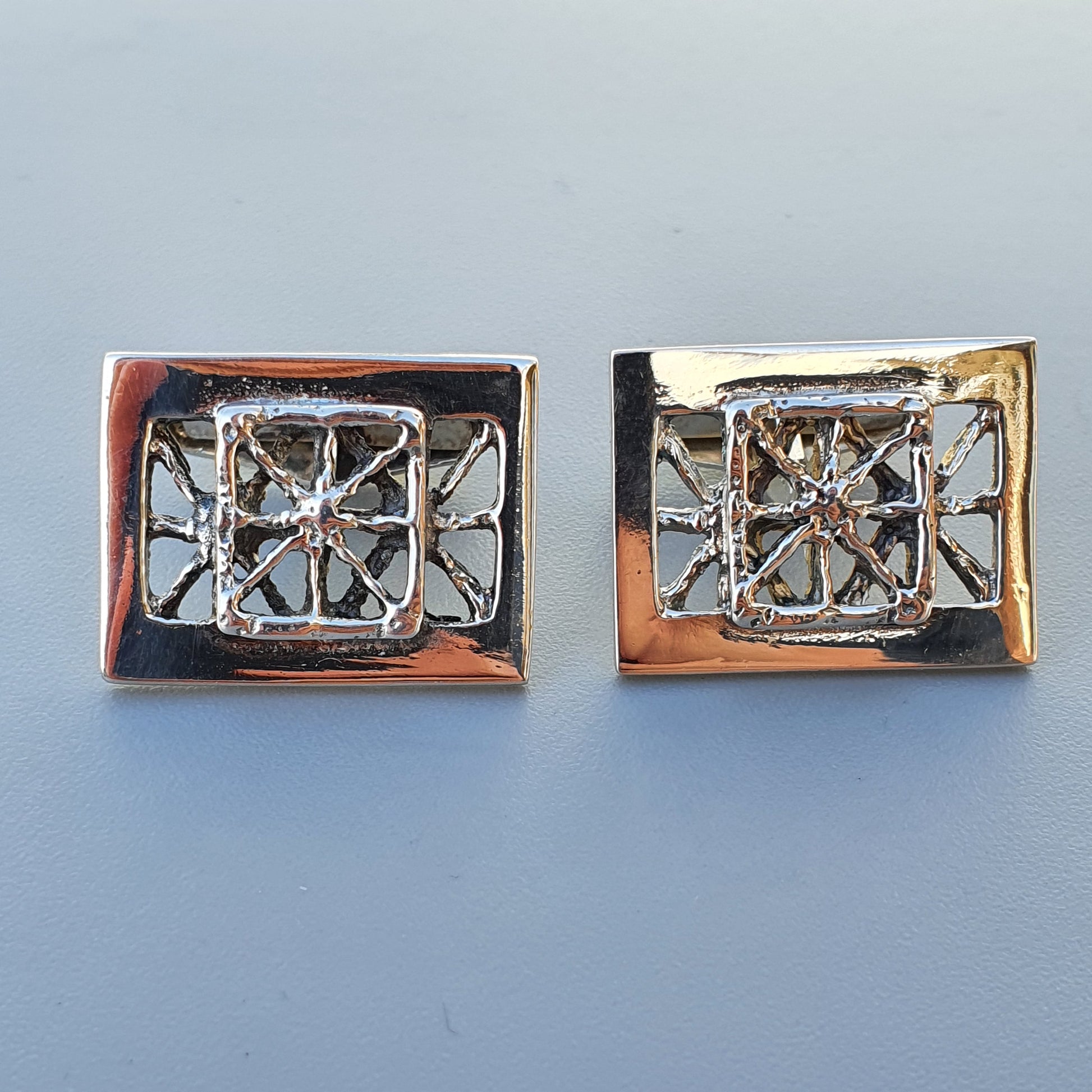 Pair of rectangular cufflinks with intricate geometric designs.