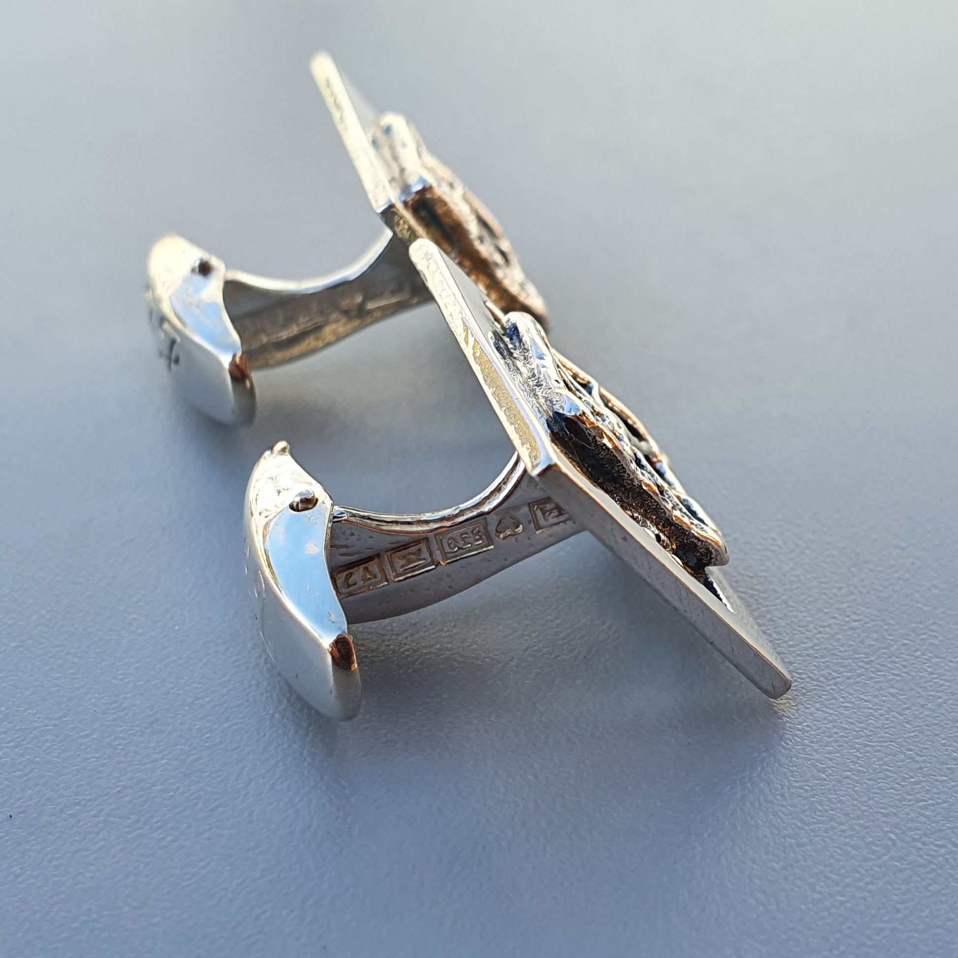 Silver cufflink shaped like an airplane or jet.