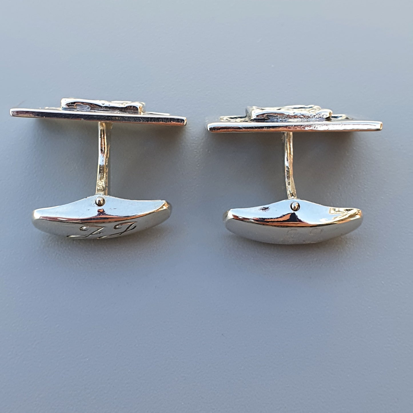 Pair of silver cufflinks with oval-shaped faces and T-bar fasteners.