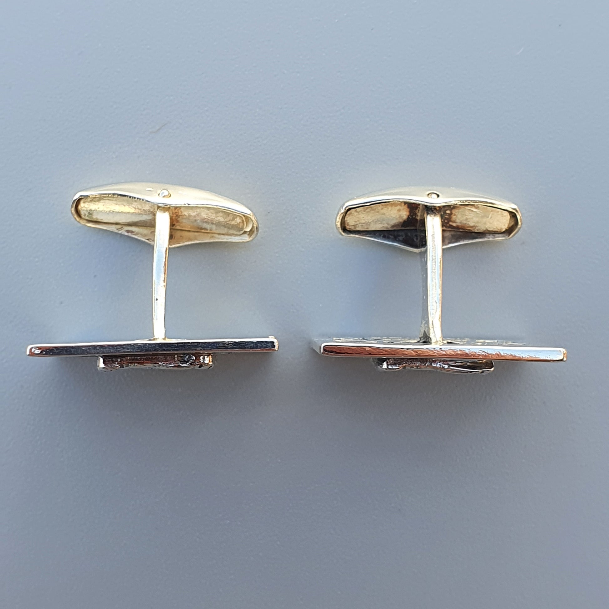 Pair of gold and silver cufflinks with rectangular shapes.