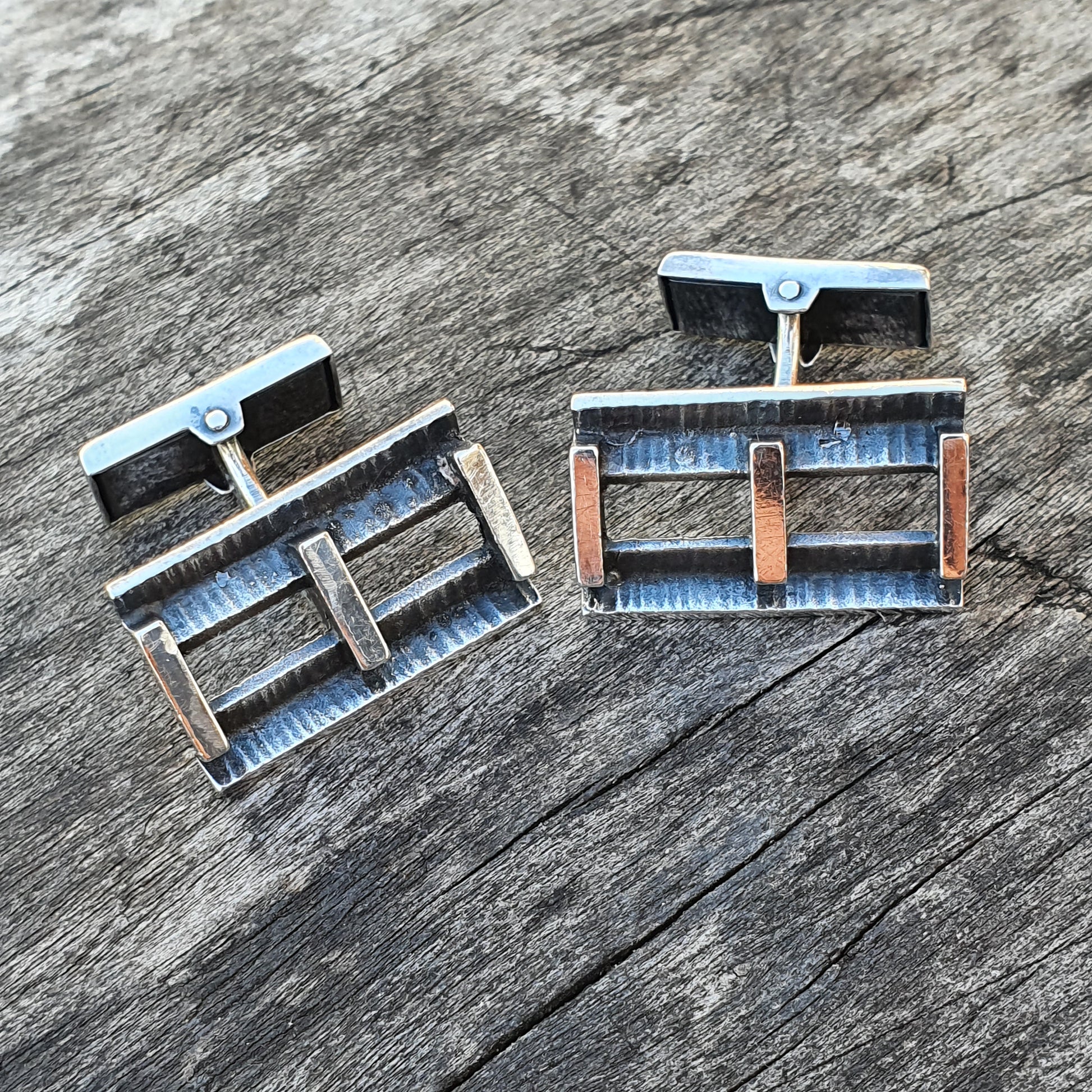 Pair of rectangular metal cufflinks with geometric designs.