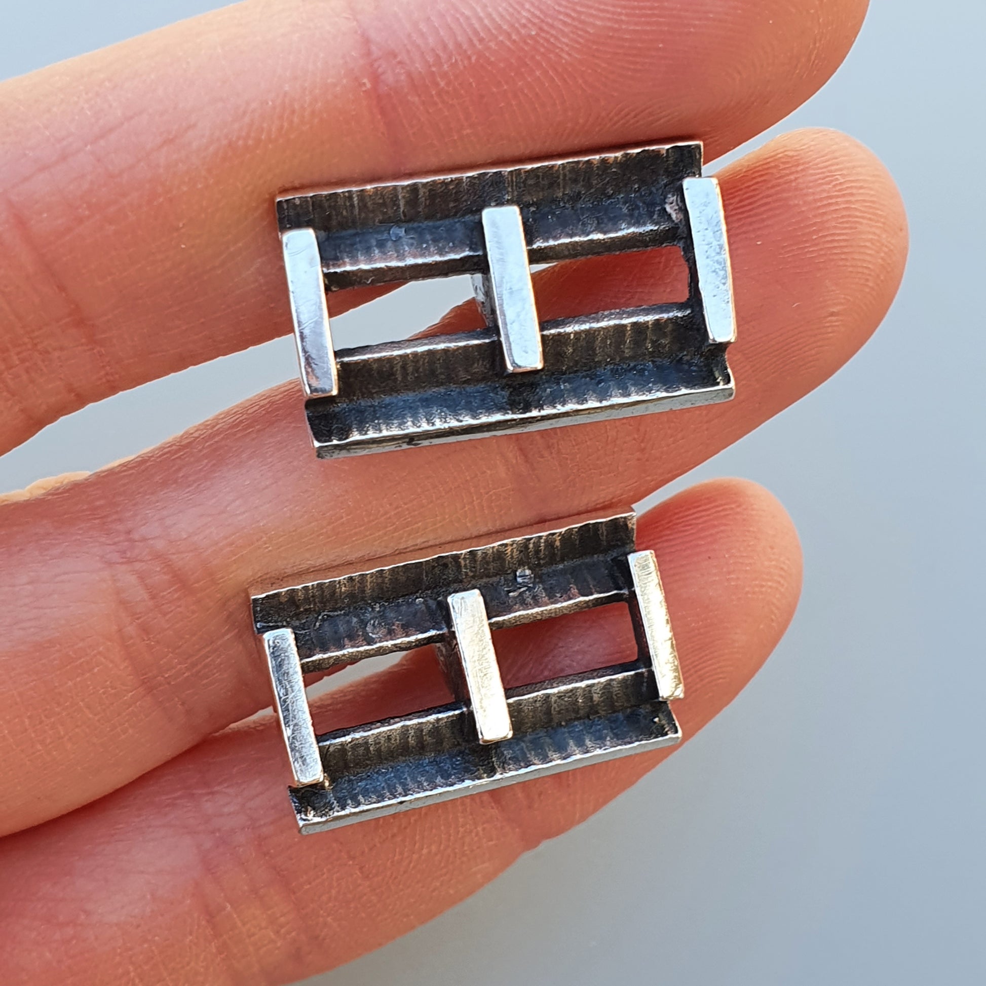 Metal belt buckles with two parallel bars across the center.