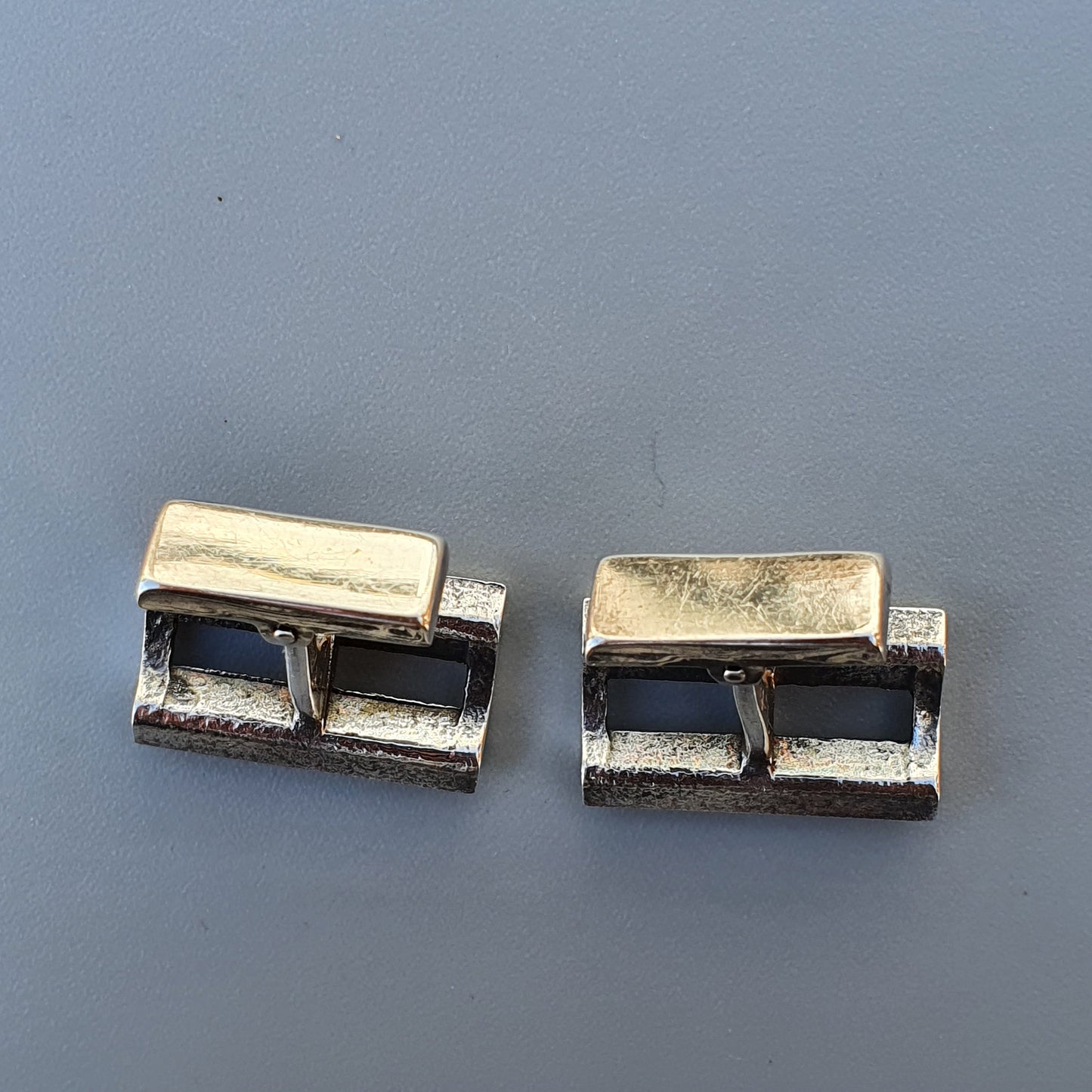 Pair of silver-toned rectangular cufflinks with a hinged design.