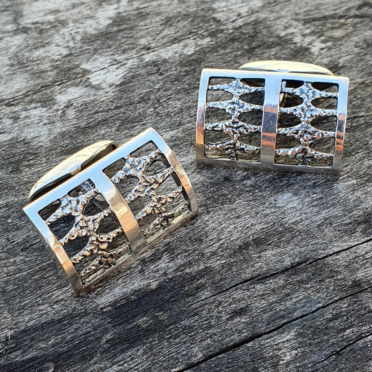 Pair of square silver cufflinks with intricate tree-like designs.