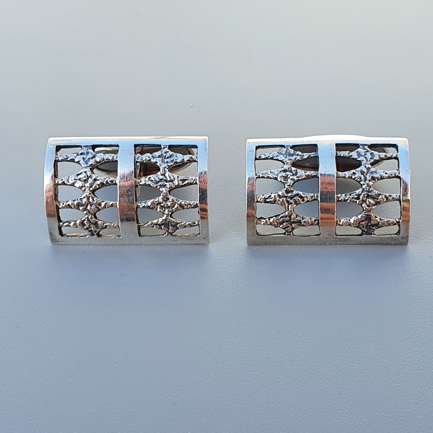 Pair of silver cufflinks with textured rectangular designs.