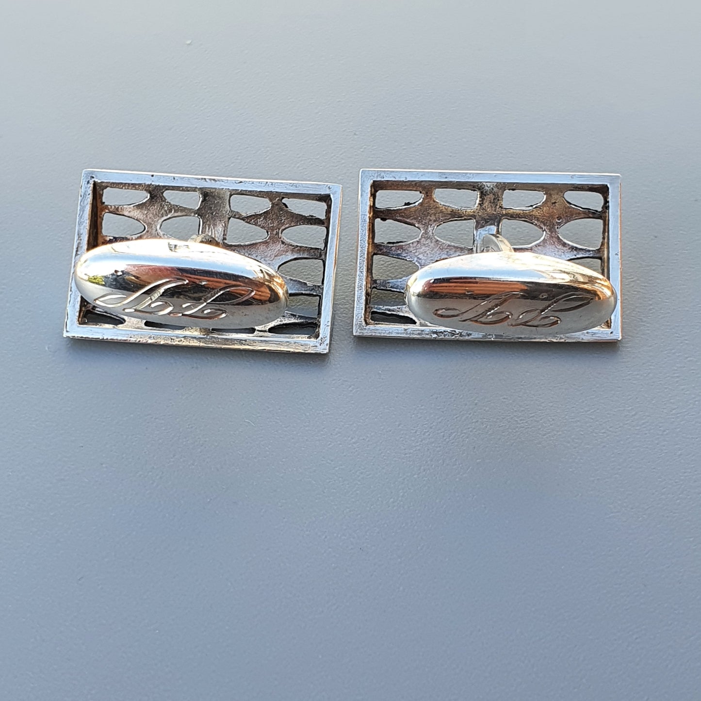 Pair of rectangular silver cufflinks with geometric cutout patterns.