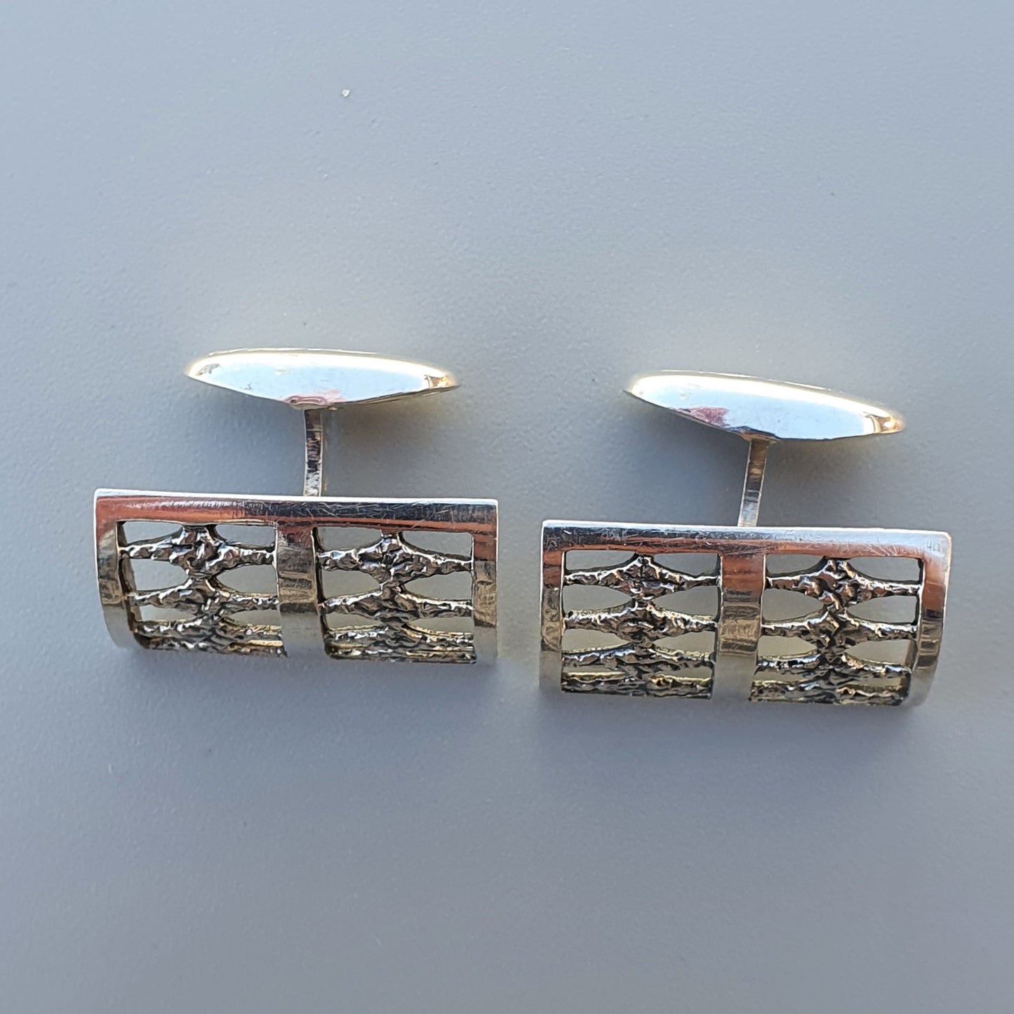 Pair of rectangular silver cufflinks with textured geometric designs.