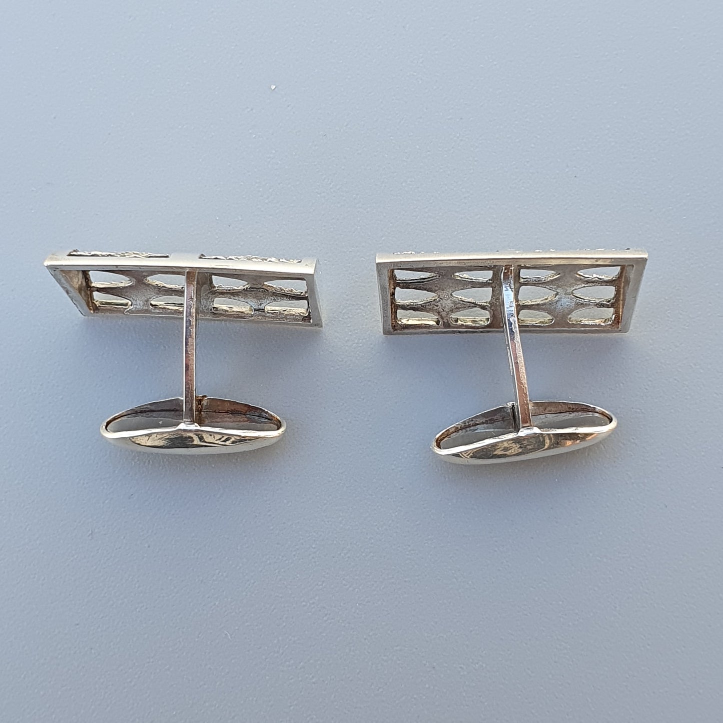 Pair of rectangular silver cufflinks with geometric cutout designs.