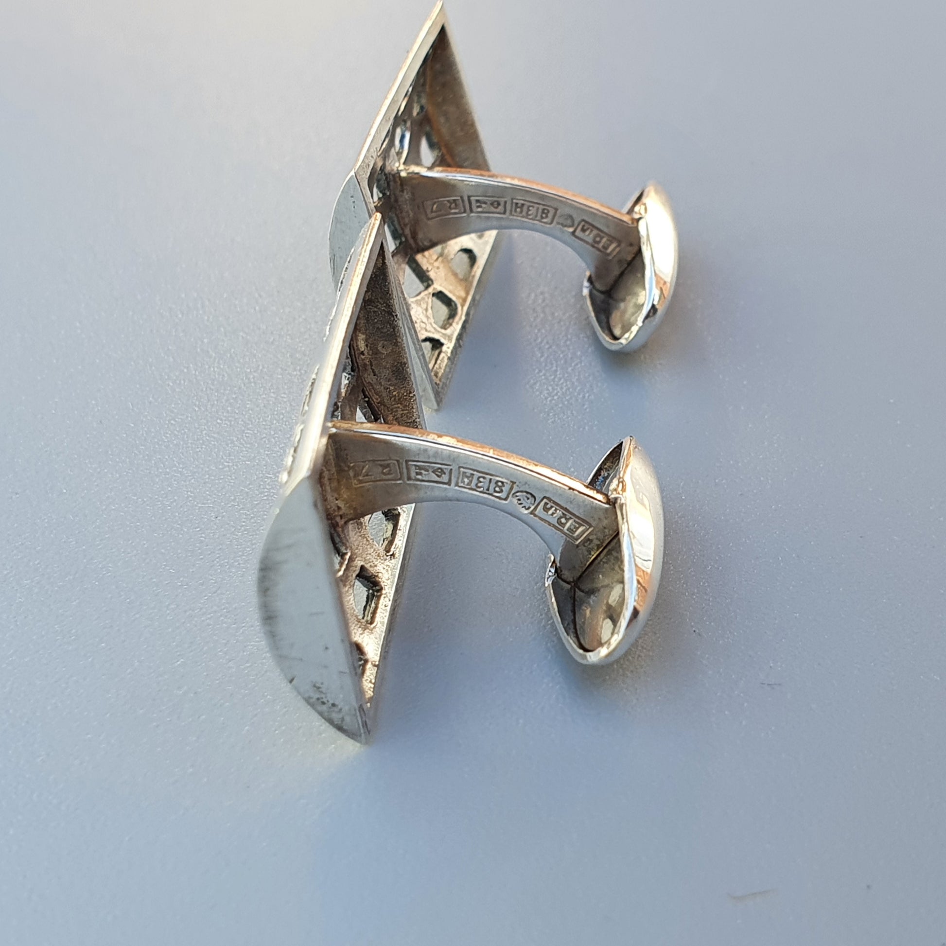 Silver cufflinks shaped like the letter E.