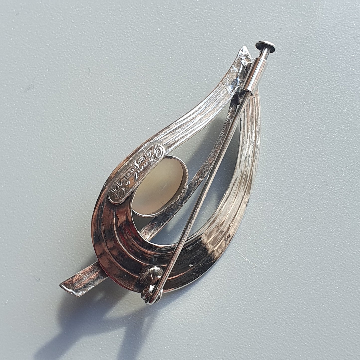 Ornate silver brooch with a teardrop shape and decorative engravings.