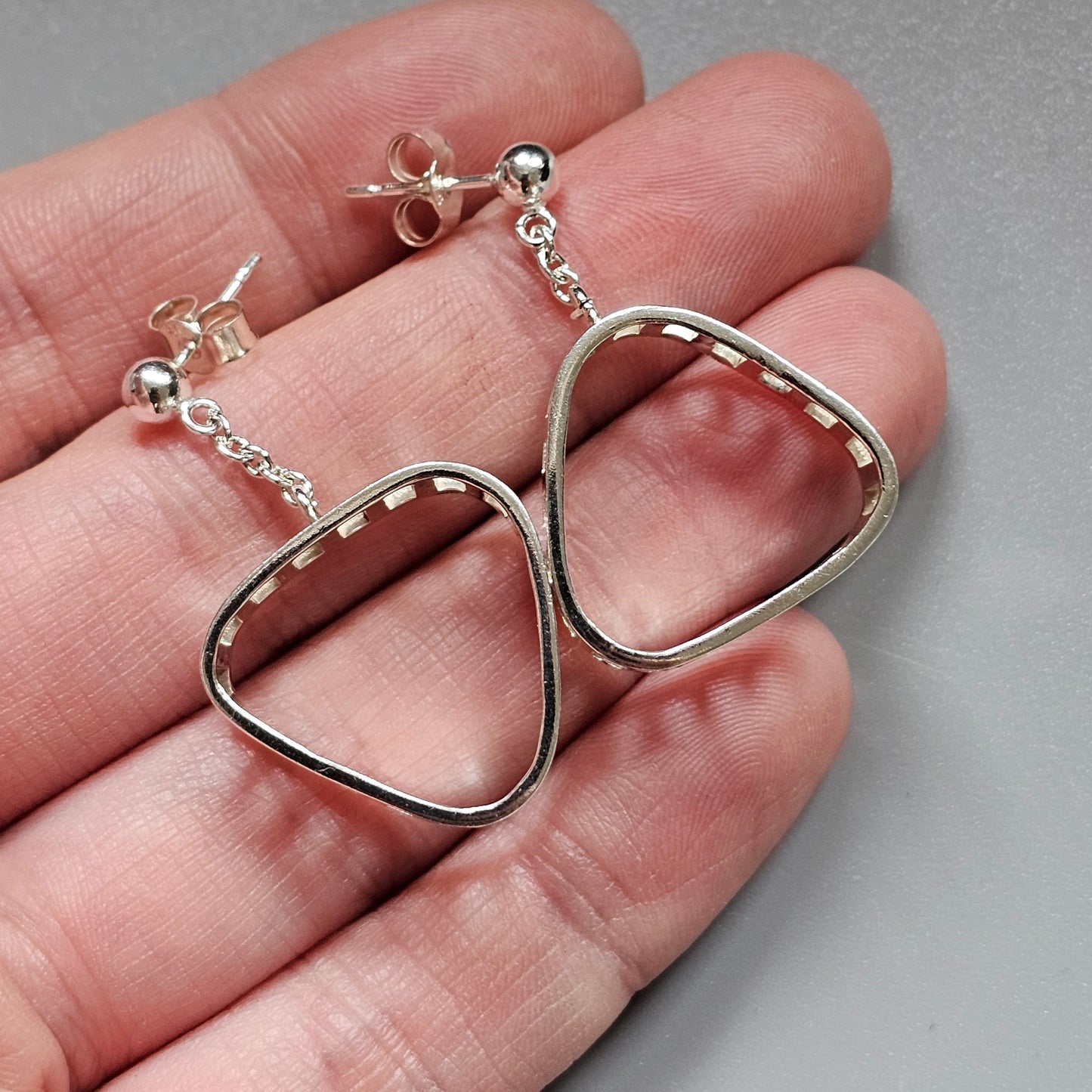 Silver earrings with abstract triangular-shaped loops.