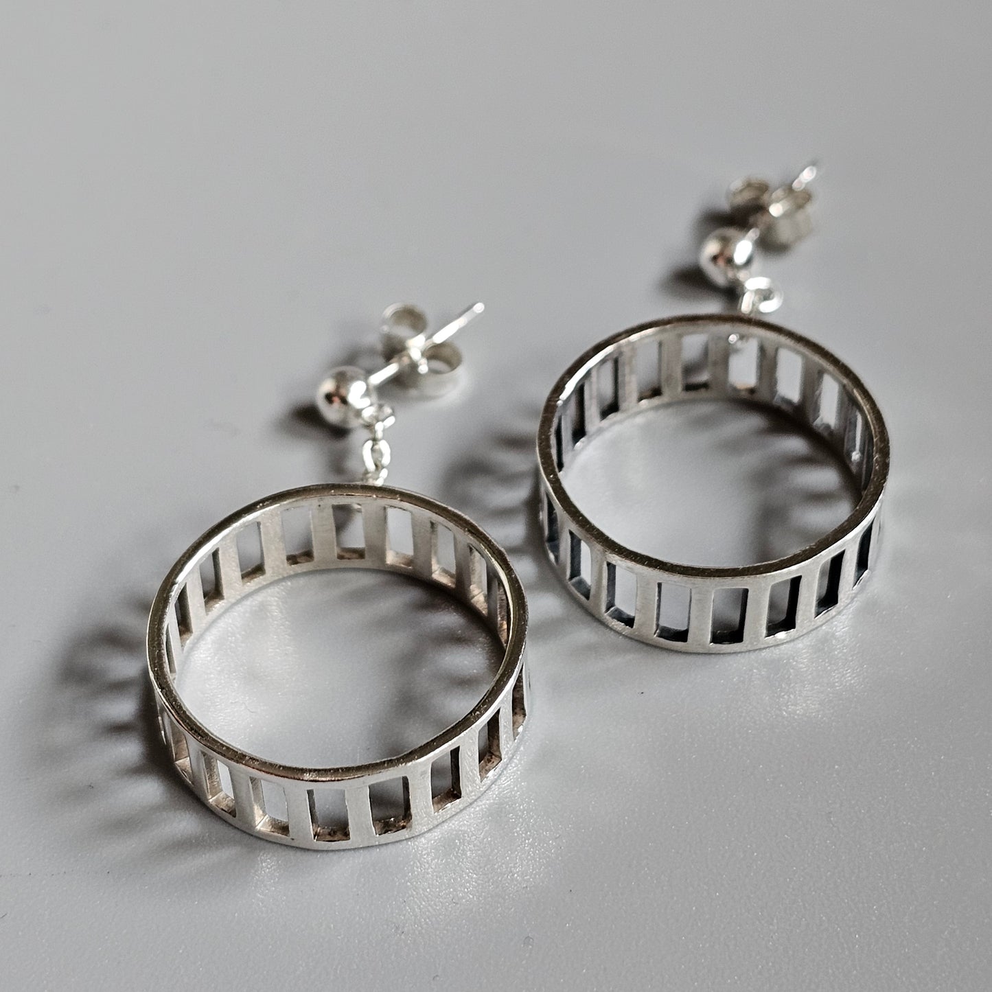 Silver hoop earrings with vertical bar designs.