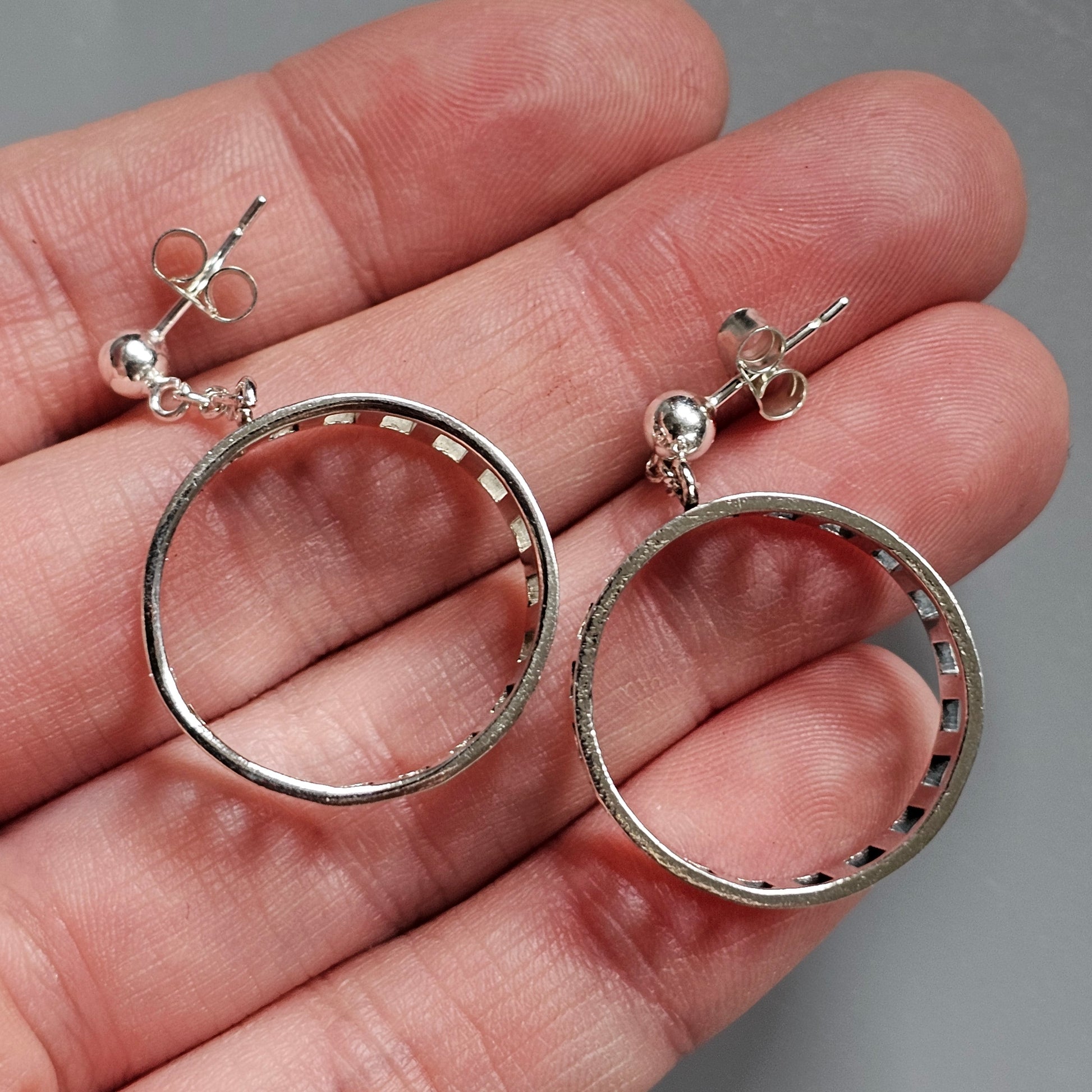 Pair of circular silver hoop earrings with small stud attachments.