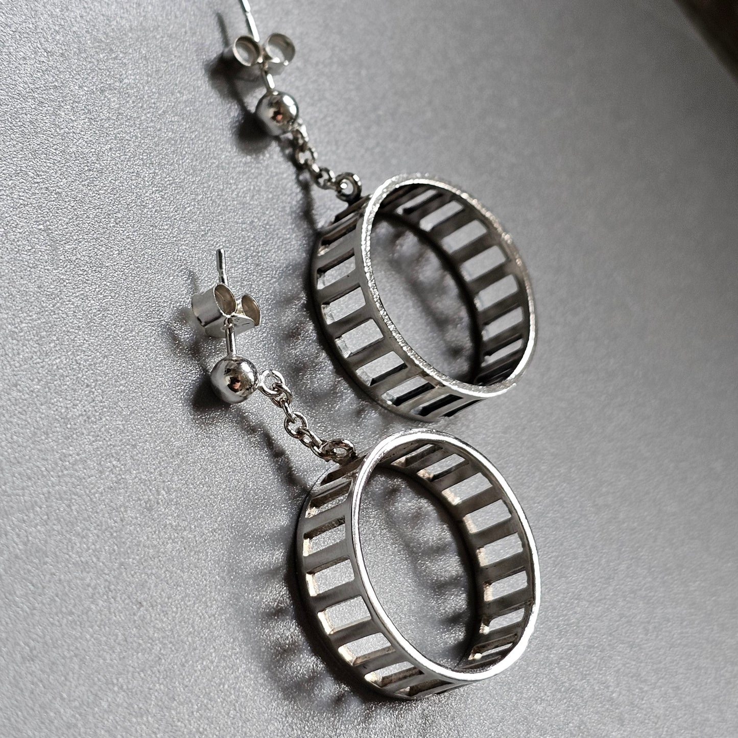 Pair of silver hoop earrings with vertical bar designs.