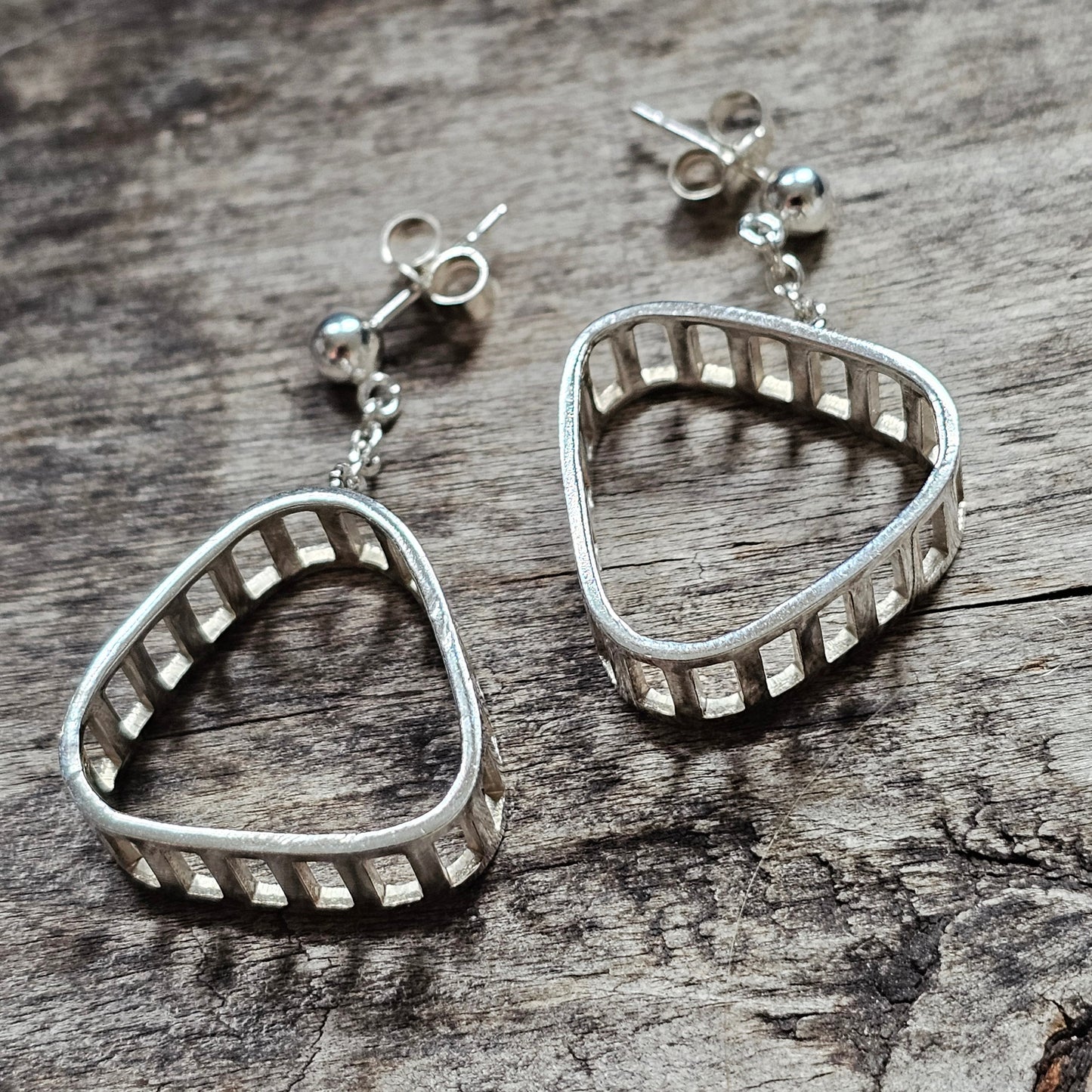 Silver earrings shaped like vampire fangs or teeth.