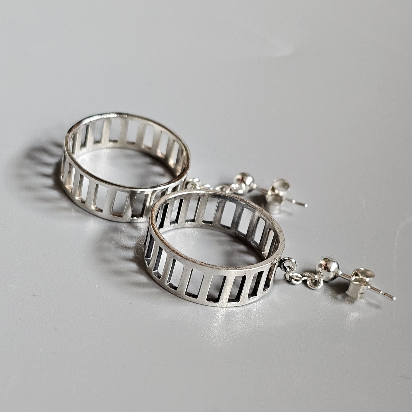 Pair of silver hoop earrings with a ladder-like design and small dangling stars.