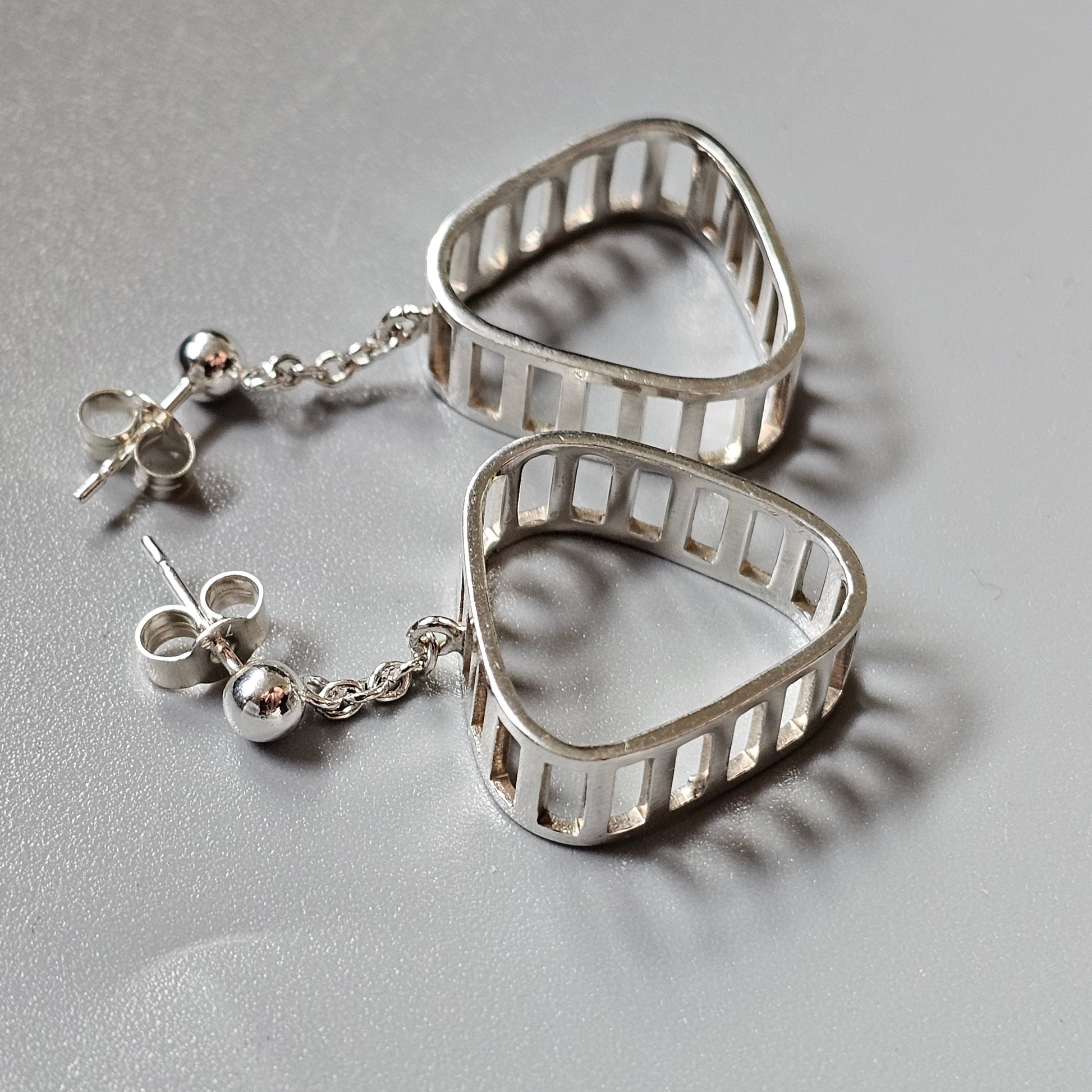 Silver earrings featuring triangular shapes with ladder-like cutouts.