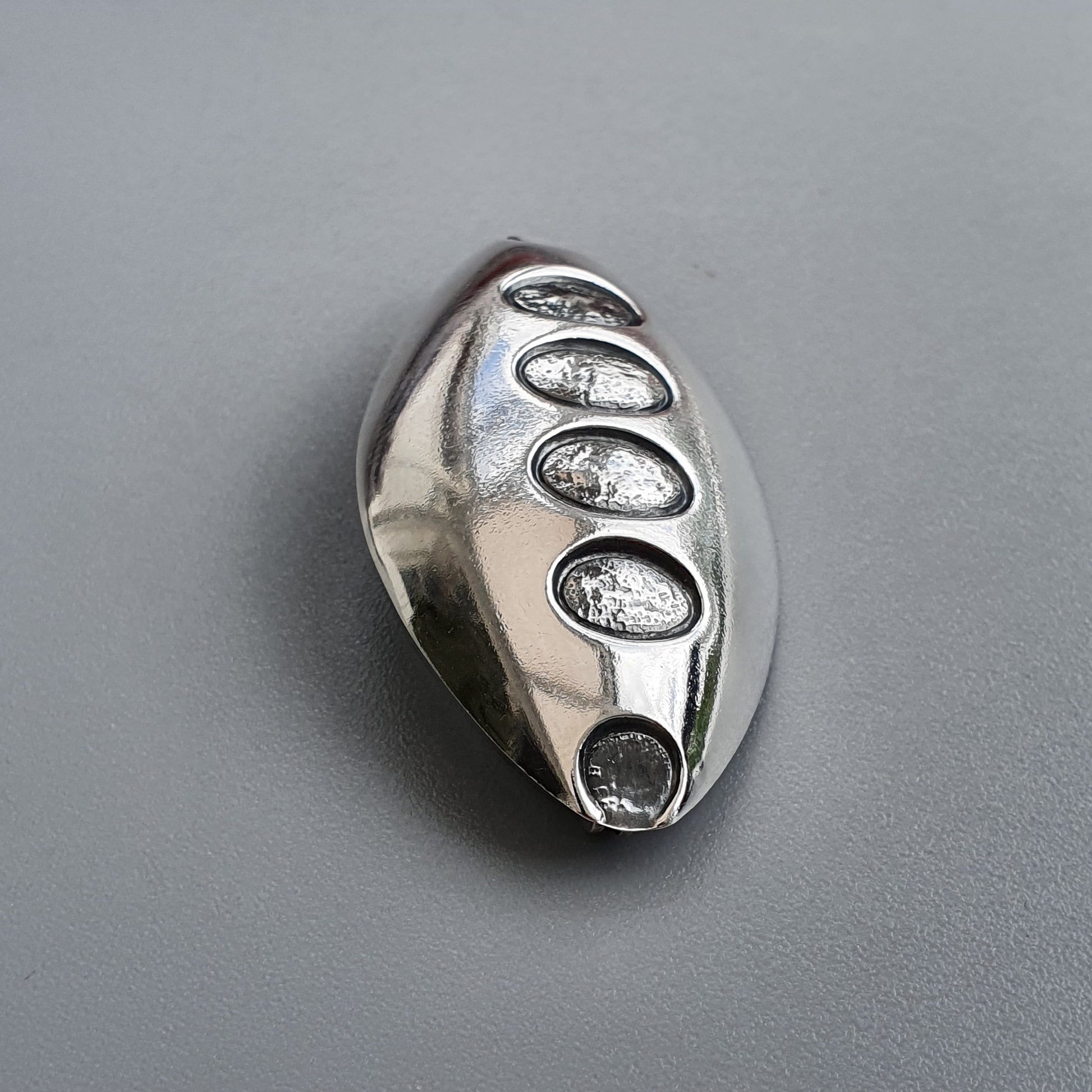 Silver ring with five oval indentations arranged in a row.