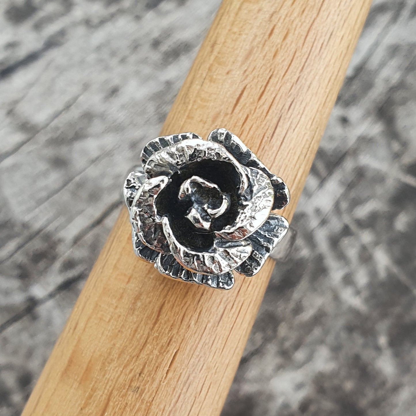 Silver rose-shaped ring with detailed metalwork petals.