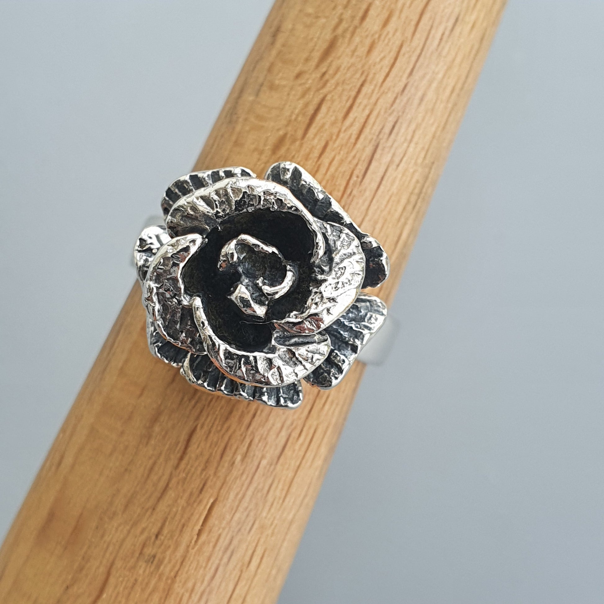 Silver ring shaped like a detailed rose bloom with darkened accents.