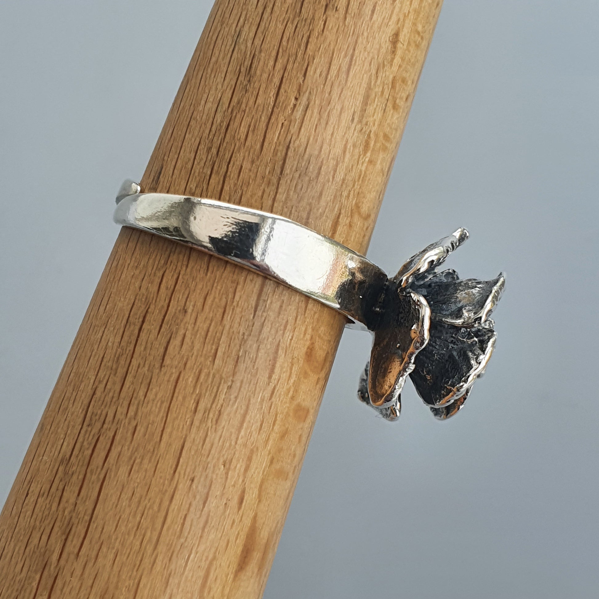 Silver ring with a small black butterfly-shaped charm attached.