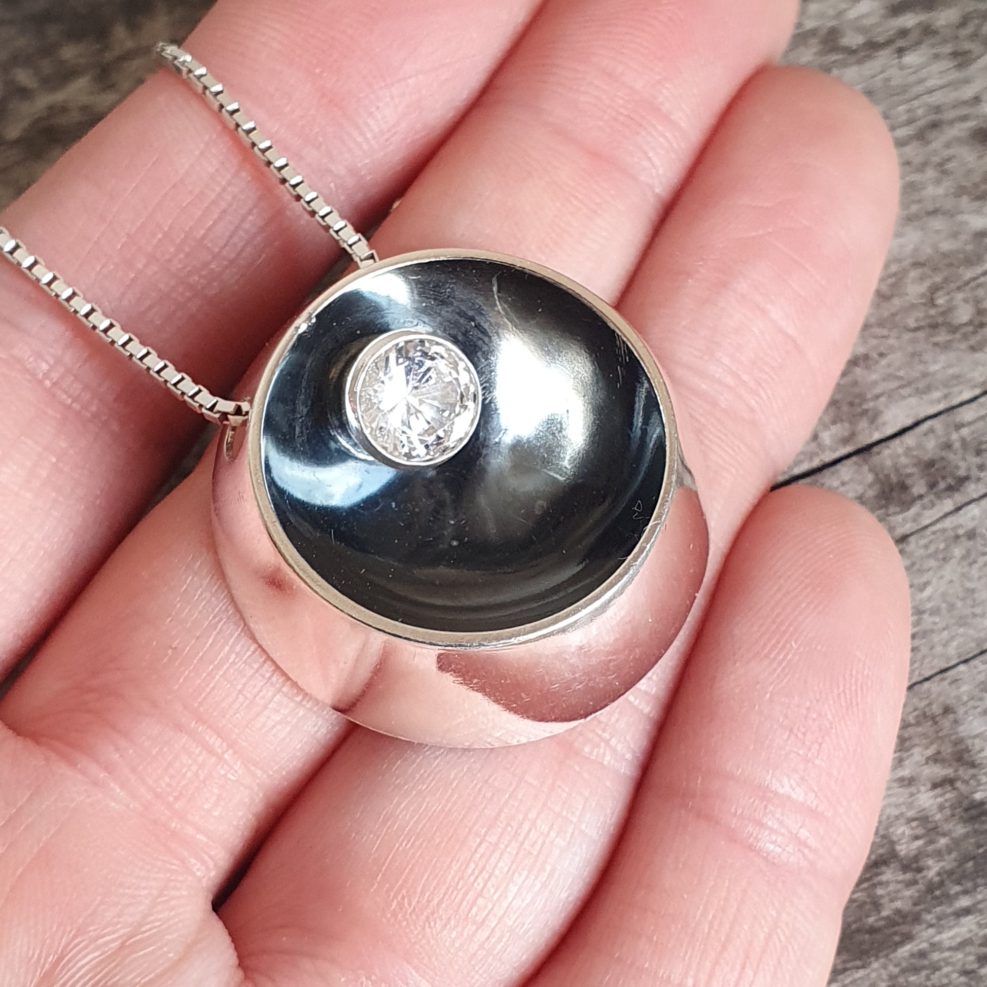 Spherical pendant necklace with a black dome and inset diamond.