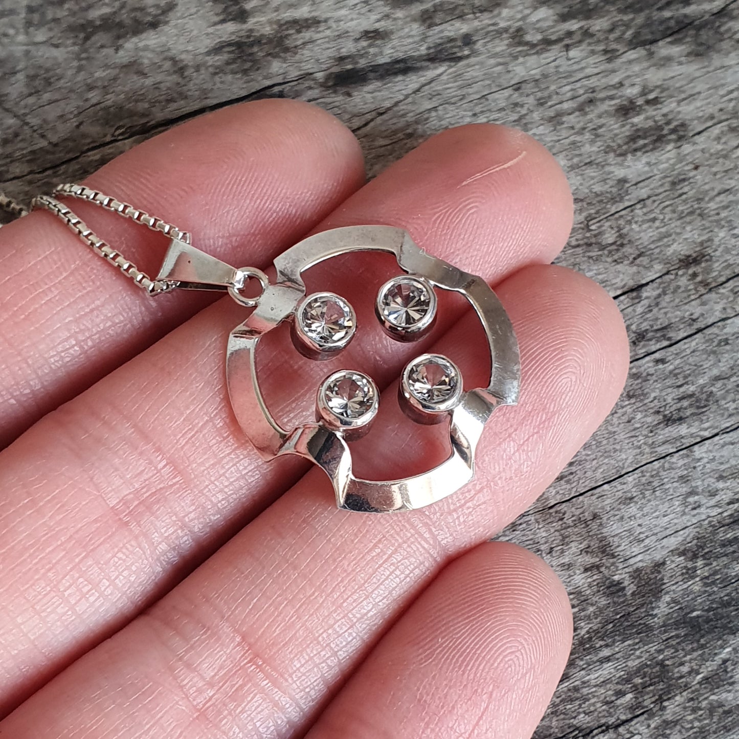 Silver pendant necklace with four small gemstones in a circular design.