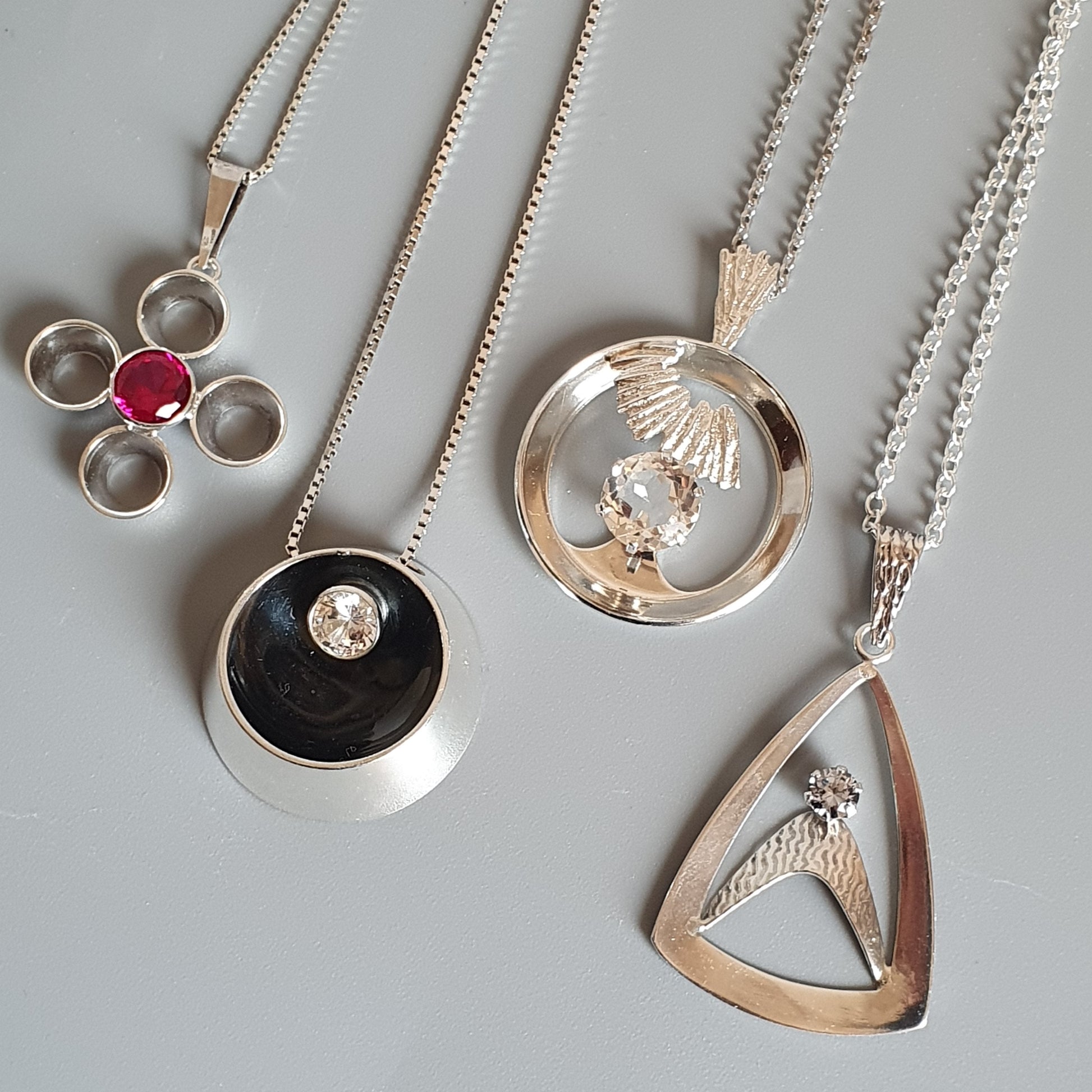 Collection of silver pendant necklaces with various designs.