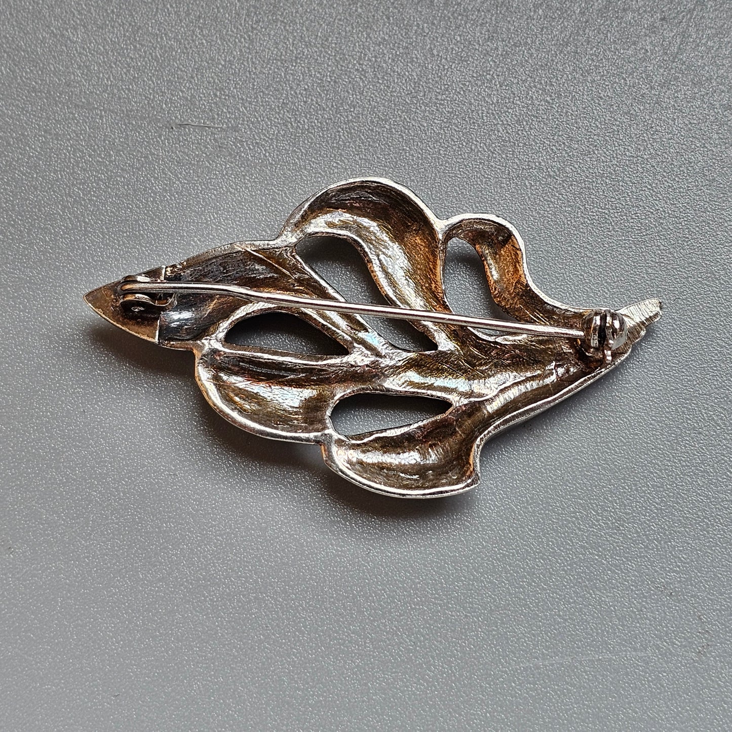 Silver brooch or pin shaped like a stylized leaf or botanical design.