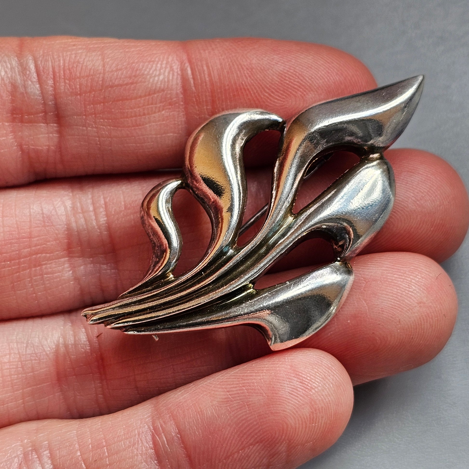 Silver brooch or pin with an abstract leaf or floral design.