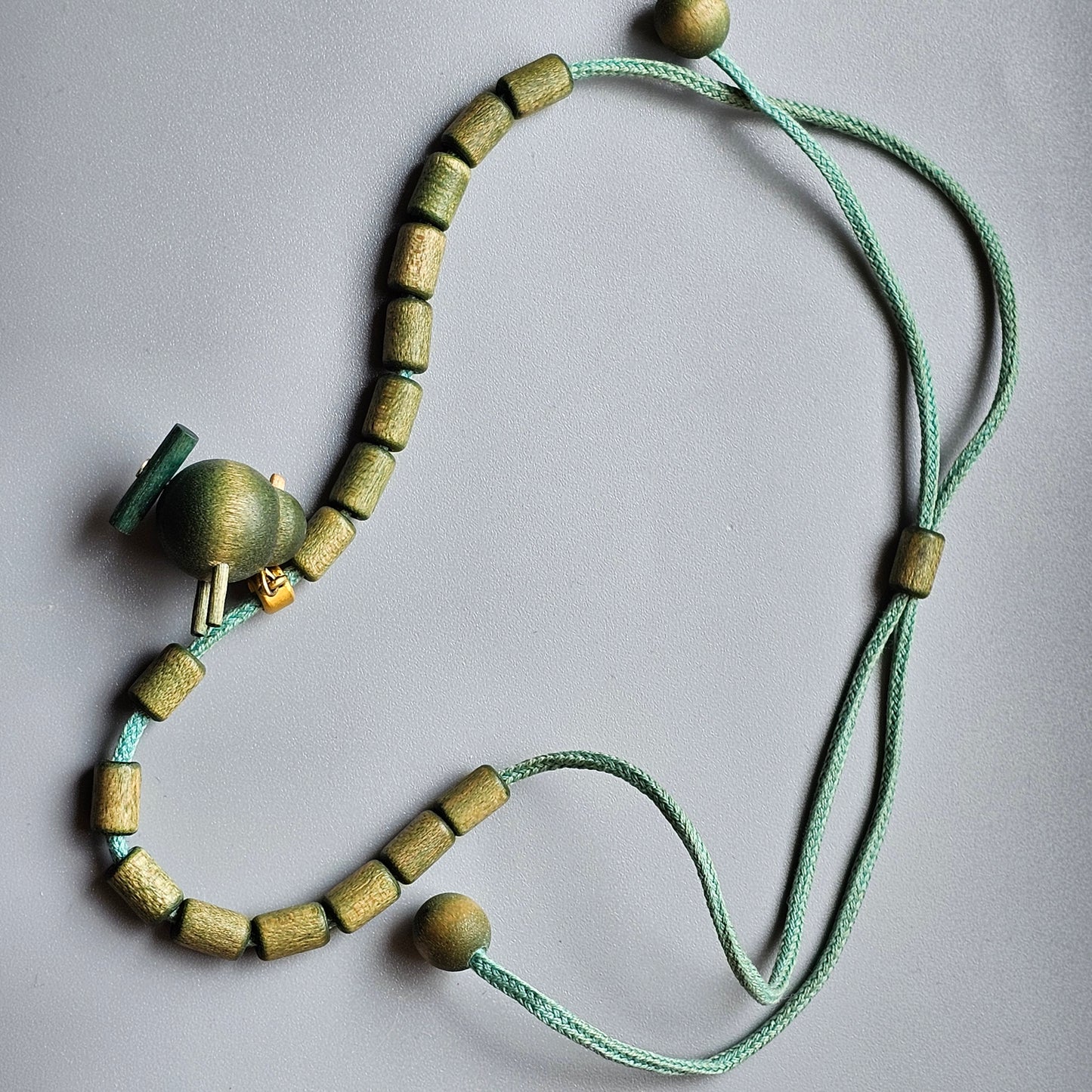 Beaded necklace with mint green cord and yellow-green wooden beads.