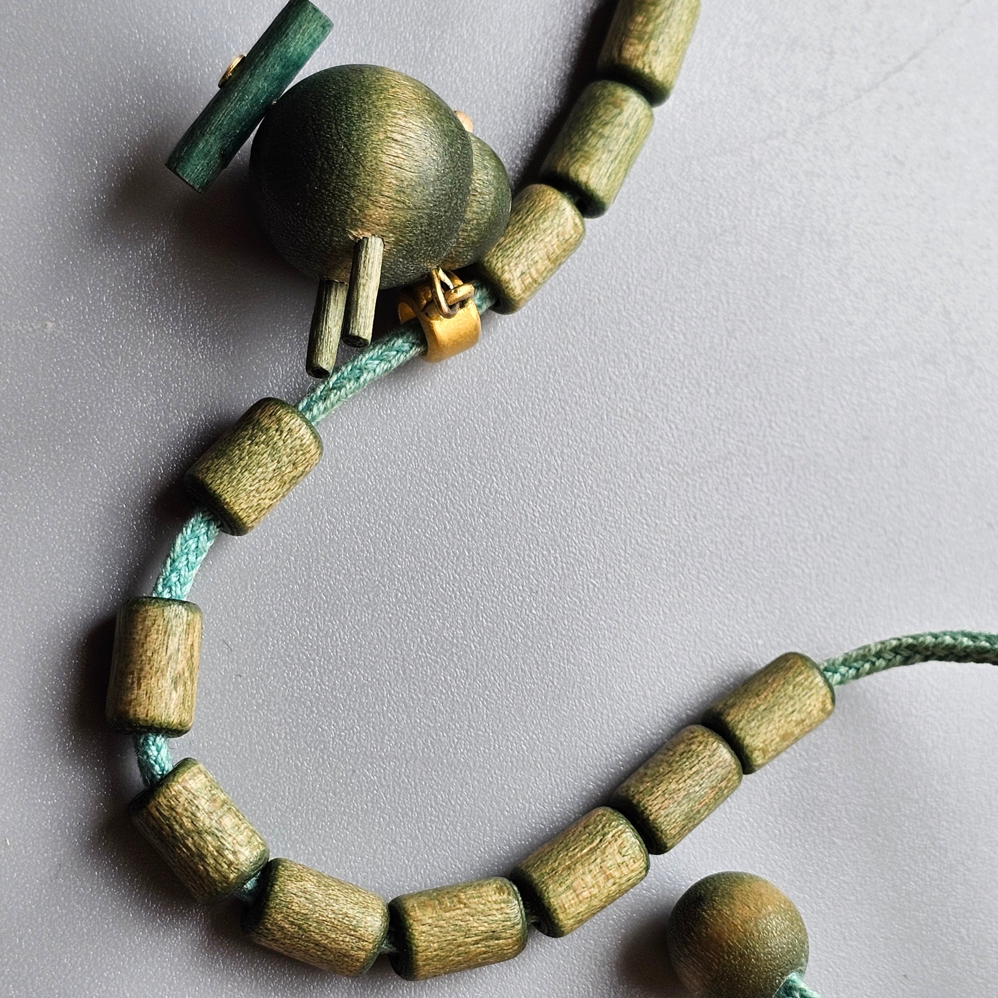 Beaded necklace or bracelet with green and wooden elements.