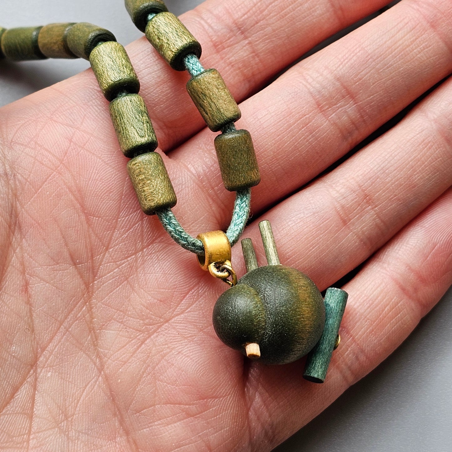 Necklace with wooden beads and a small teapot-shaped pendant.