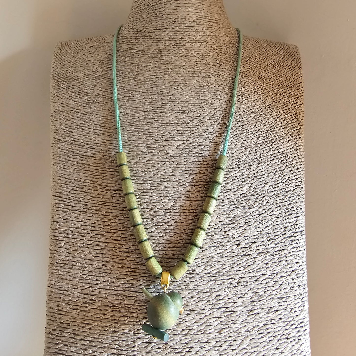 Necklace with pale green beads and a stone pendant on a mint-colored cord.