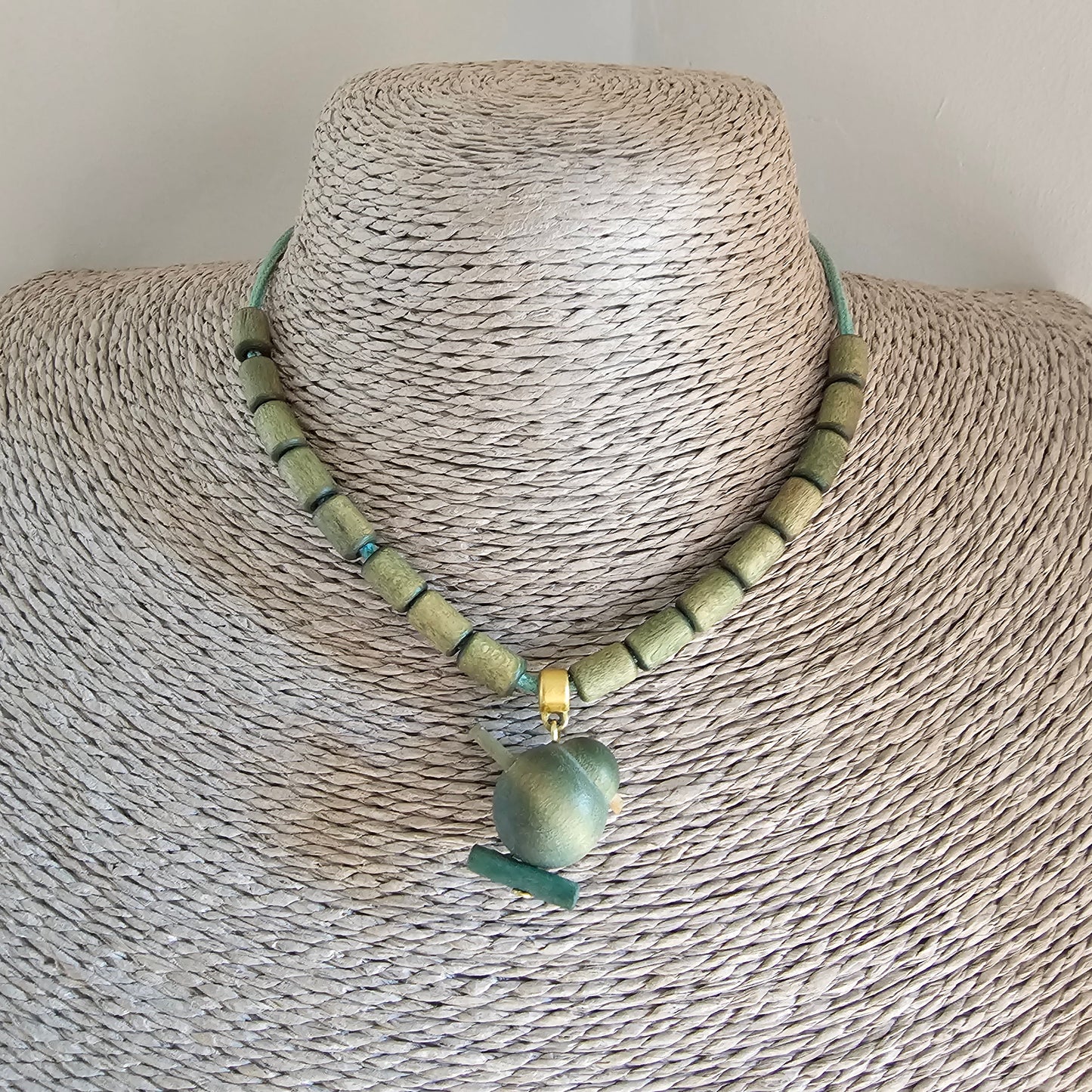 Pale green beaded necklace with a turquoise-colored bell-shaped pendant.