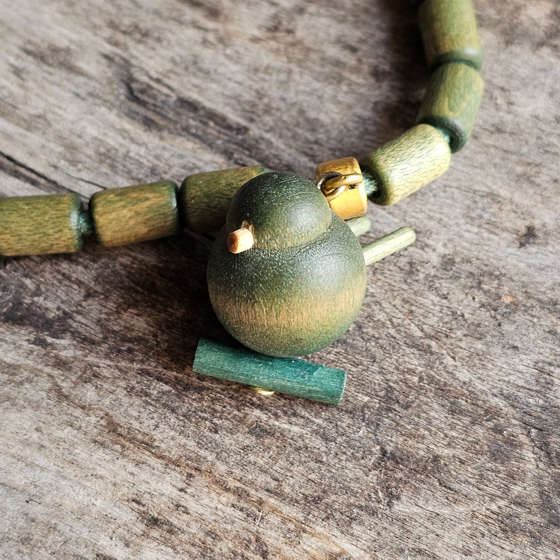 Green wooden bird bead on a necklace.