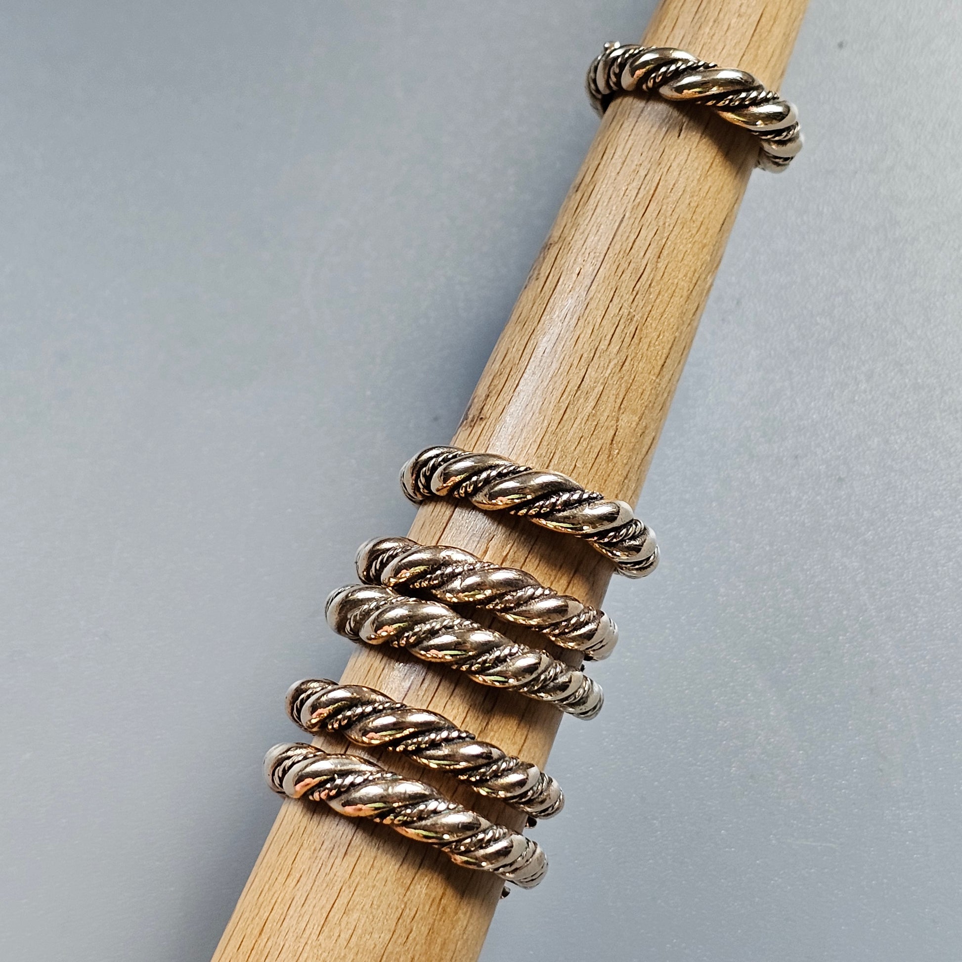 Twisted metal rings stacked on a wooden dowel or rod.