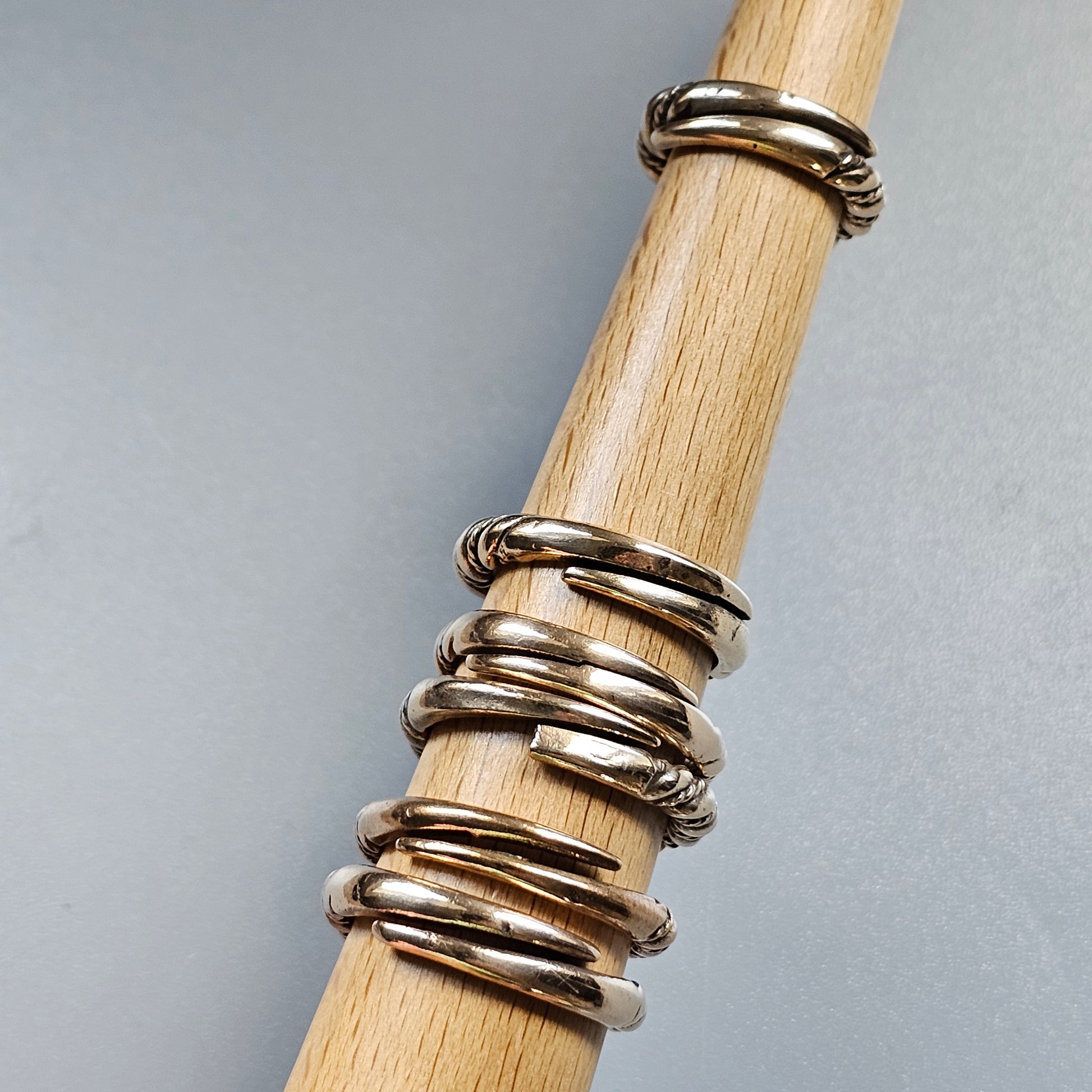 Wooden dowel or rod displaying multiple silver rings stacked along its length.