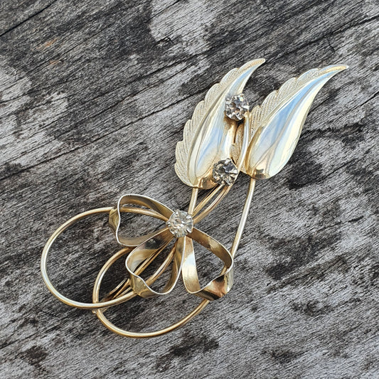 Delicate gold and enamel brooch shaped like stylized leaves or feathers with small gemstones.